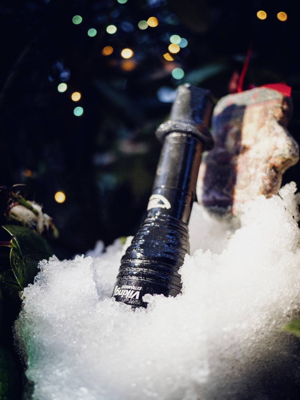 Eine schwarze Flasche im Schnee, umgeben von Natur und Lichtern.
