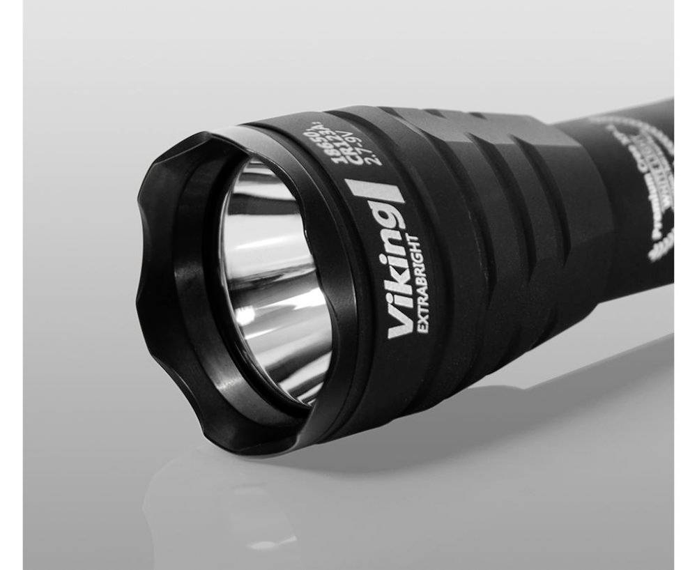 Eine schwarze Taschenlampe liegt auf einer glatten Oberfläche, mit der Aufschrift 'Viking Extra Bright' auf dem Griff.