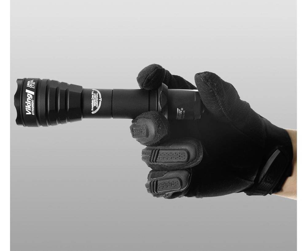 Hand in einem schwarzen Handschuh hält eine schwarze Taschenlampe.