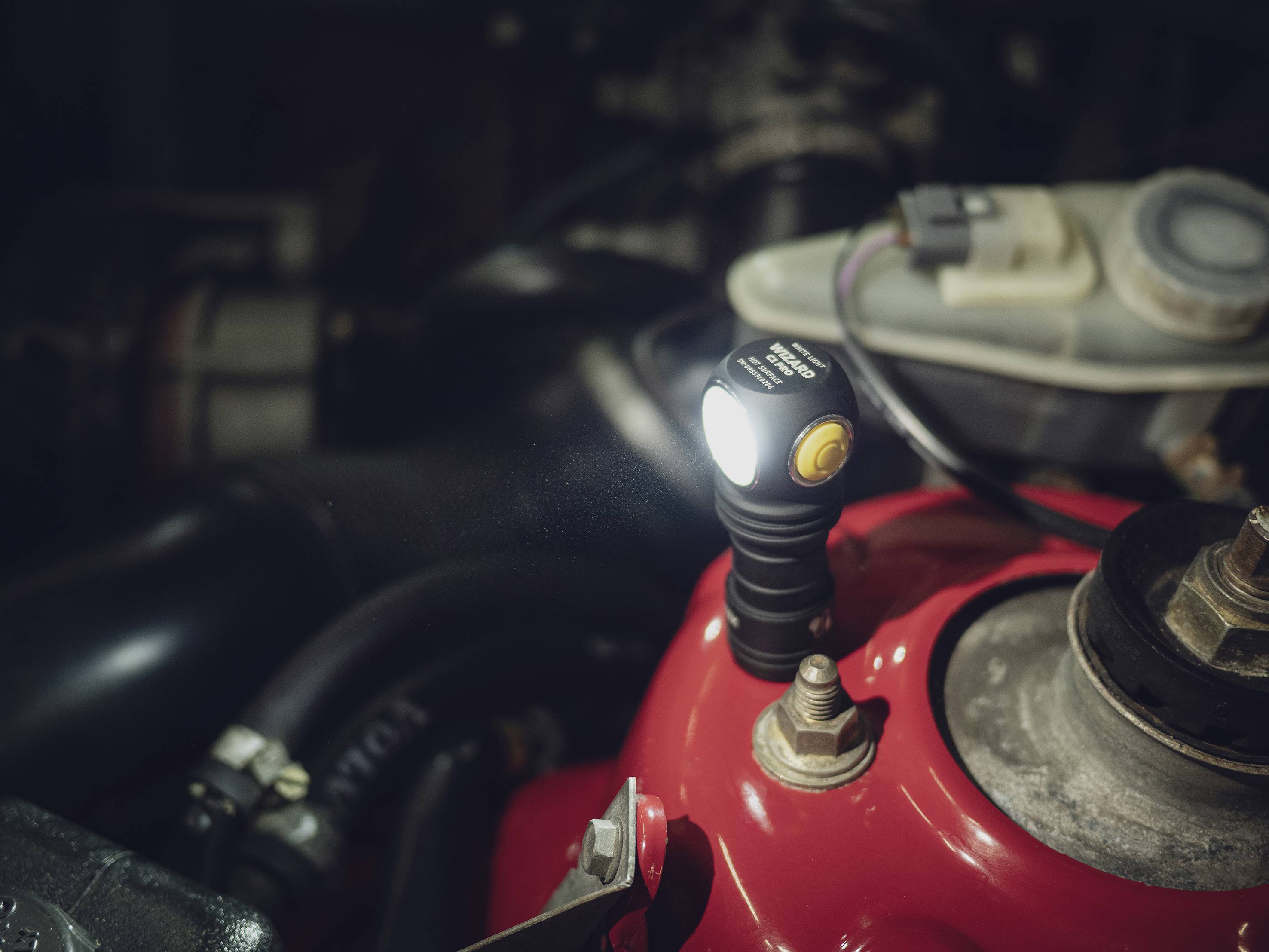 Eine LED-Lampe leuchtet im Motorraum eines Autos, beleuchtet rote und schwarze Teile.