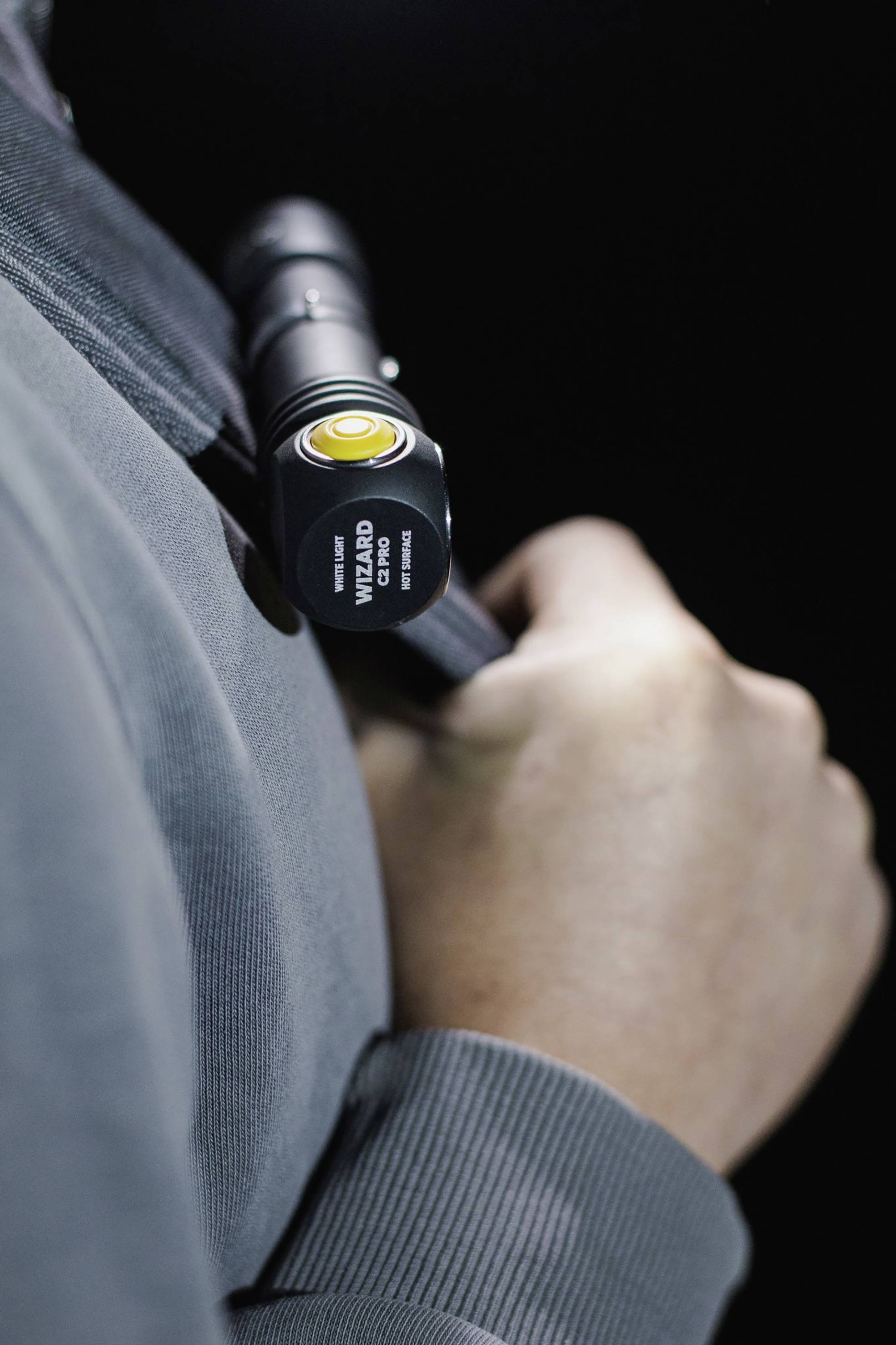Person hält eine schwarze Taschenlampe in der Hand, die nah an den Körper gehalten wird. Die Taschenlampe zeigt nach vorne.