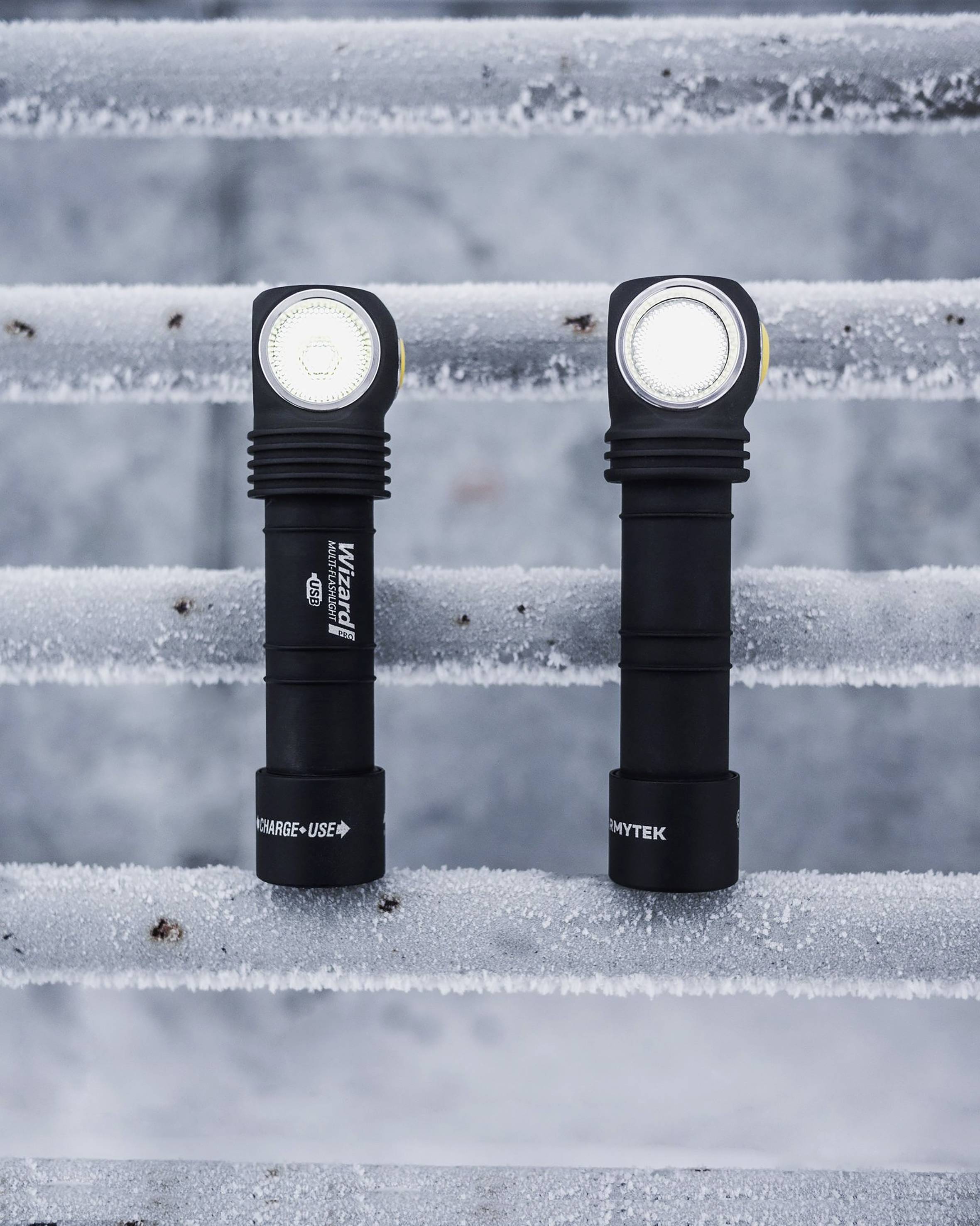 Zwei Taschenlampen stehen vertikal auf gefrorenen Metallstufen. Beide haben leuchtende LED-Lampen und schwarze Griffe.