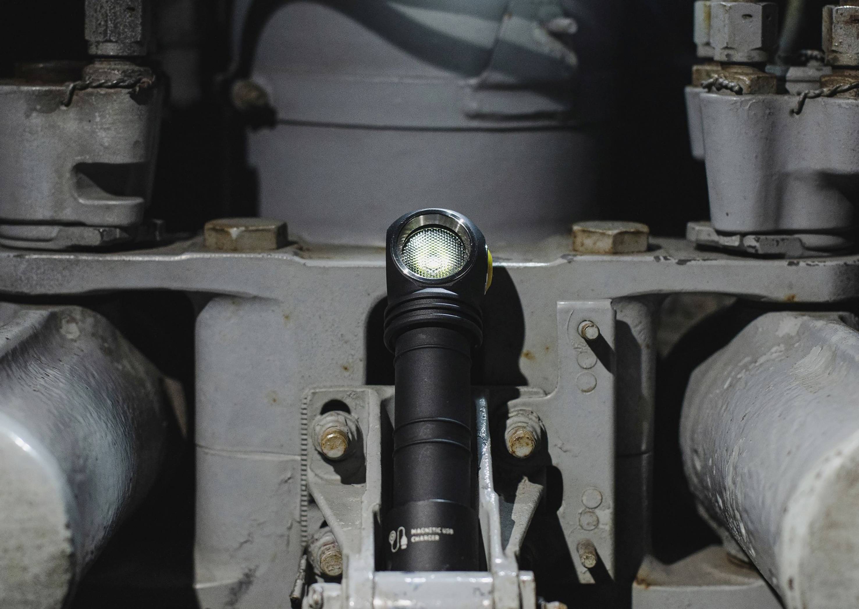 Taschenlampe leuchtet im dunklen industriellen Raum, umgeben von Metallstrukturen und Rohren.