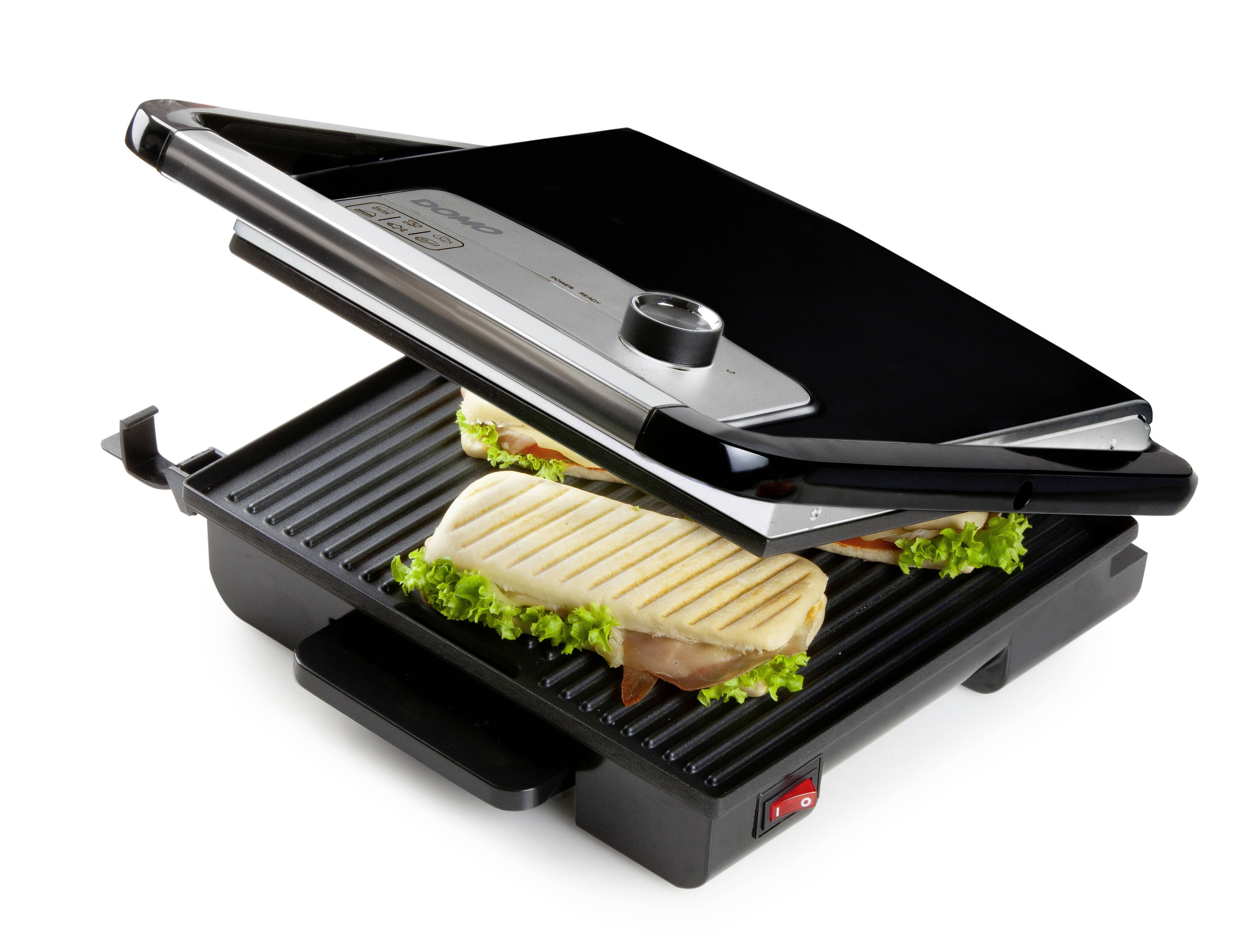 Ein geöffneter Kontaktgrill mit zwei belegten Sandwiches, darunter Salatblätter und Schinken. Der Grill hat eine Temperaturregelung.