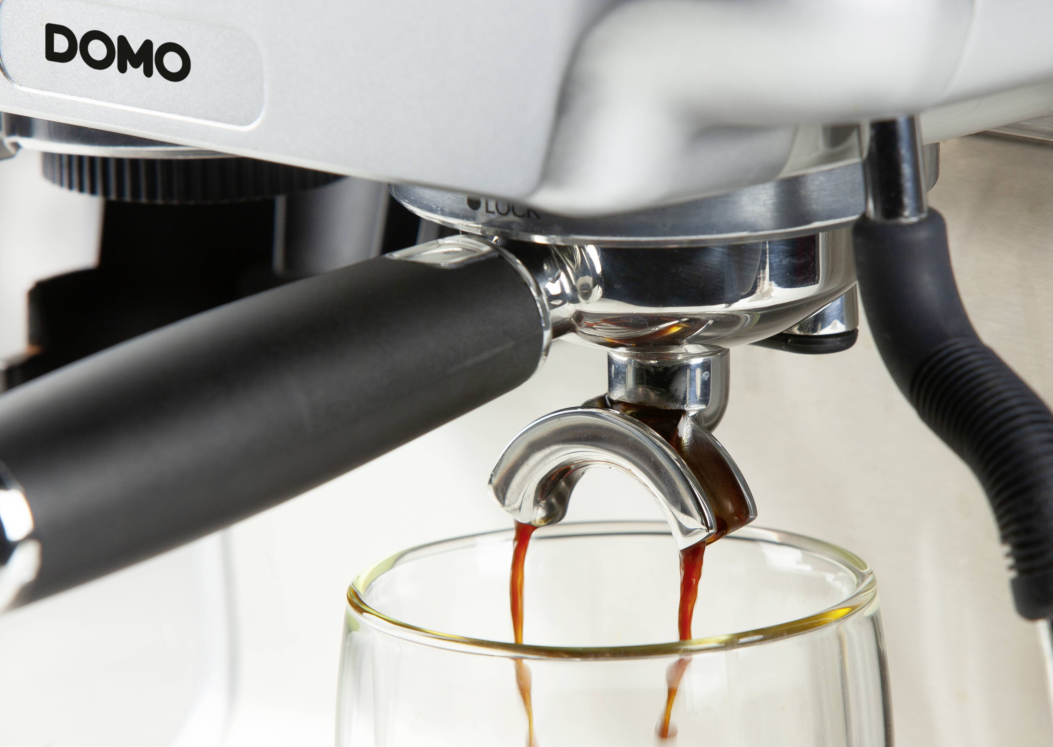 Nahaufnahme einer Kaffeemaschine, die Espresso in ein darunter stehendes Glas fließen lässt.