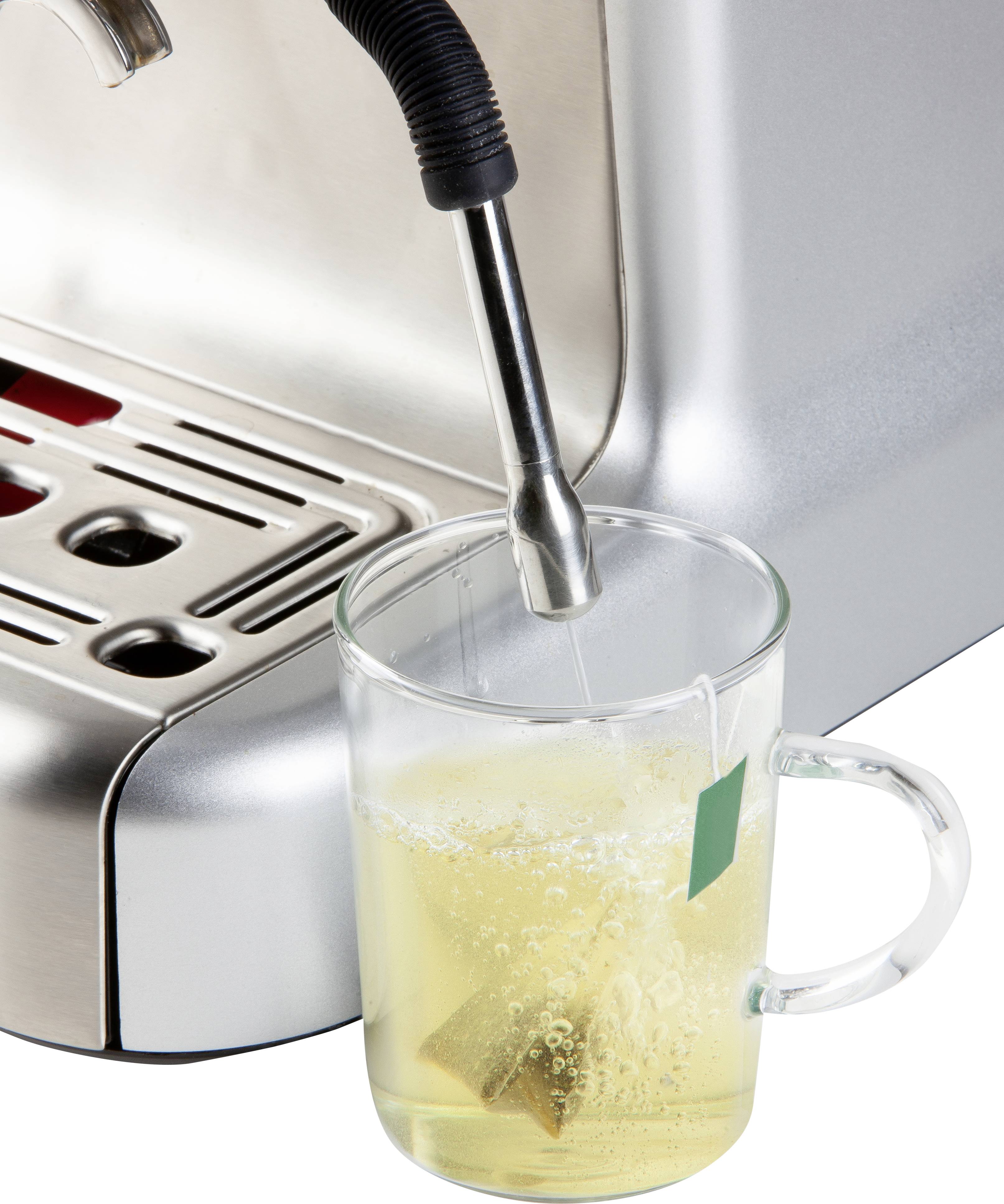 Eine Tasse mit Teebeutel wird von einer Kaffeemaschine mit heißem Wasser gefüllt.