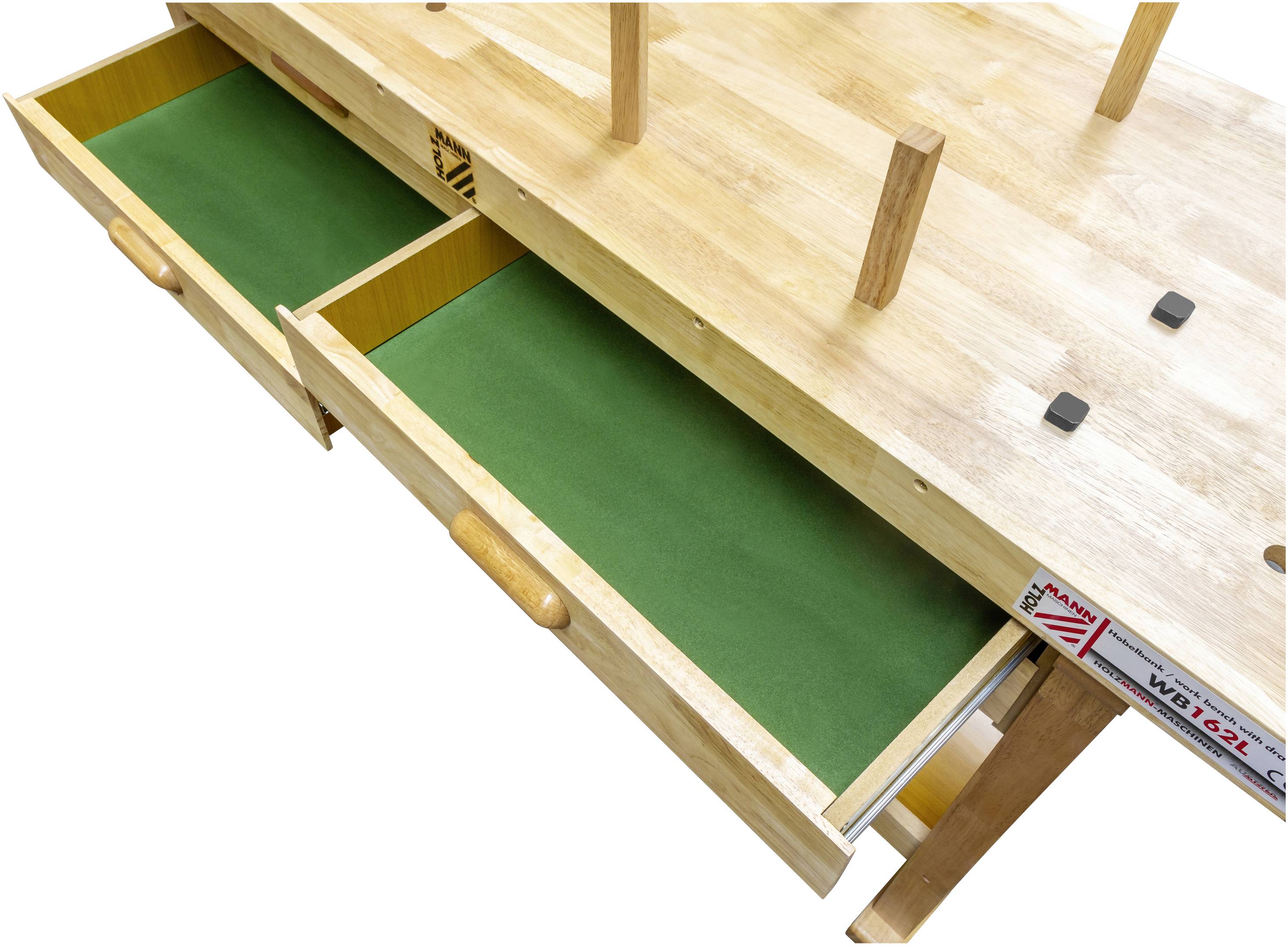 Holztisch mit grünen Samtschubladen, die herausgezogen sind. Tischbeine stehen nach oben. Die Rückseite von Maßband sichtbar.