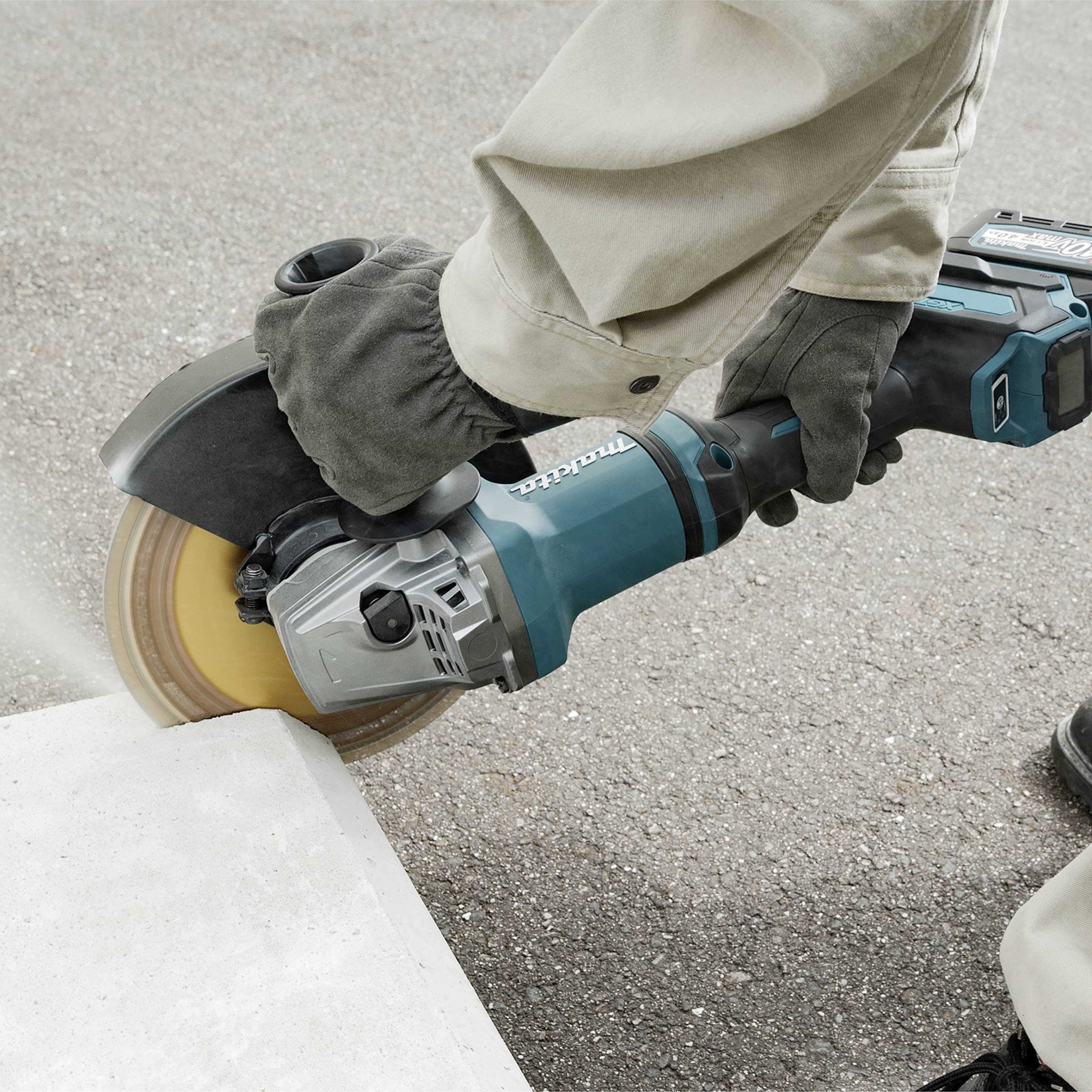 Eine Winkelschleifer wird von einer Person auf Beton eingesetzt. Das Gerät ist in Bewegung und erzeugt Staub.
