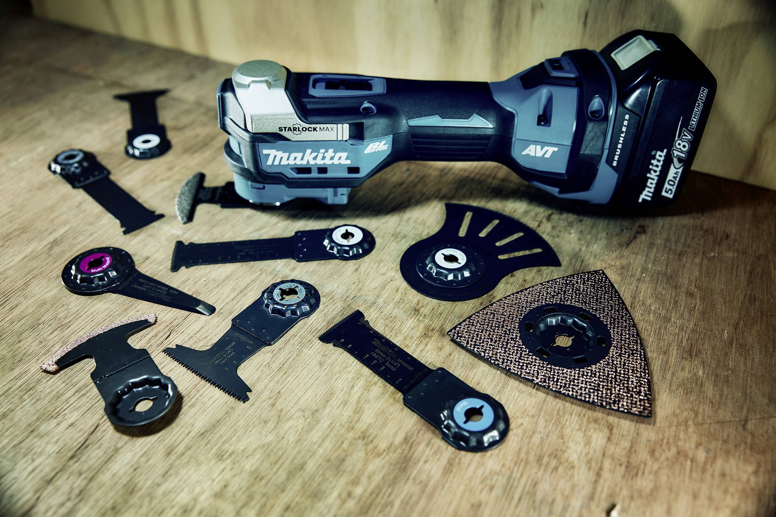 Ein blau-schwarzes oszillierendes Multitool mit verschiedenen Aufsätzen auf einem Holztisch, geeignet für Heimwerkerarbeiten.