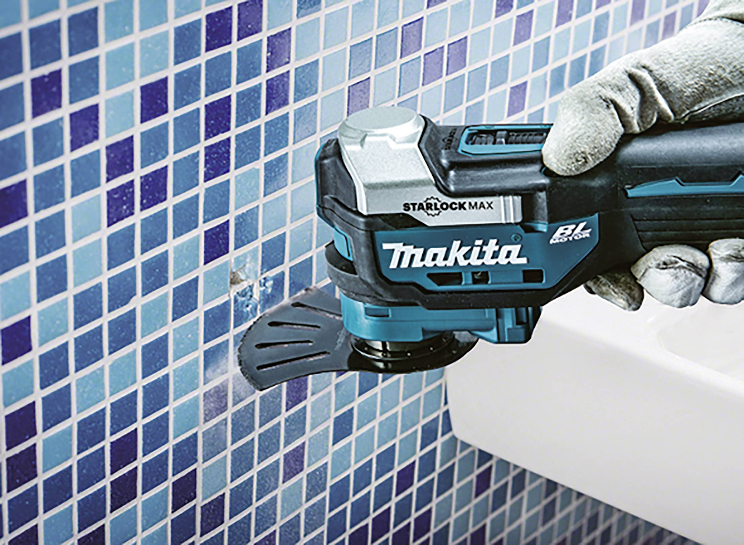 Eine Person mit Handschuhen verwendet ein blaues Oszillationswerkzeug, um Fliesen an einer mit blauen Mosaikfliesen abgedeckten Wand zu schneiden.