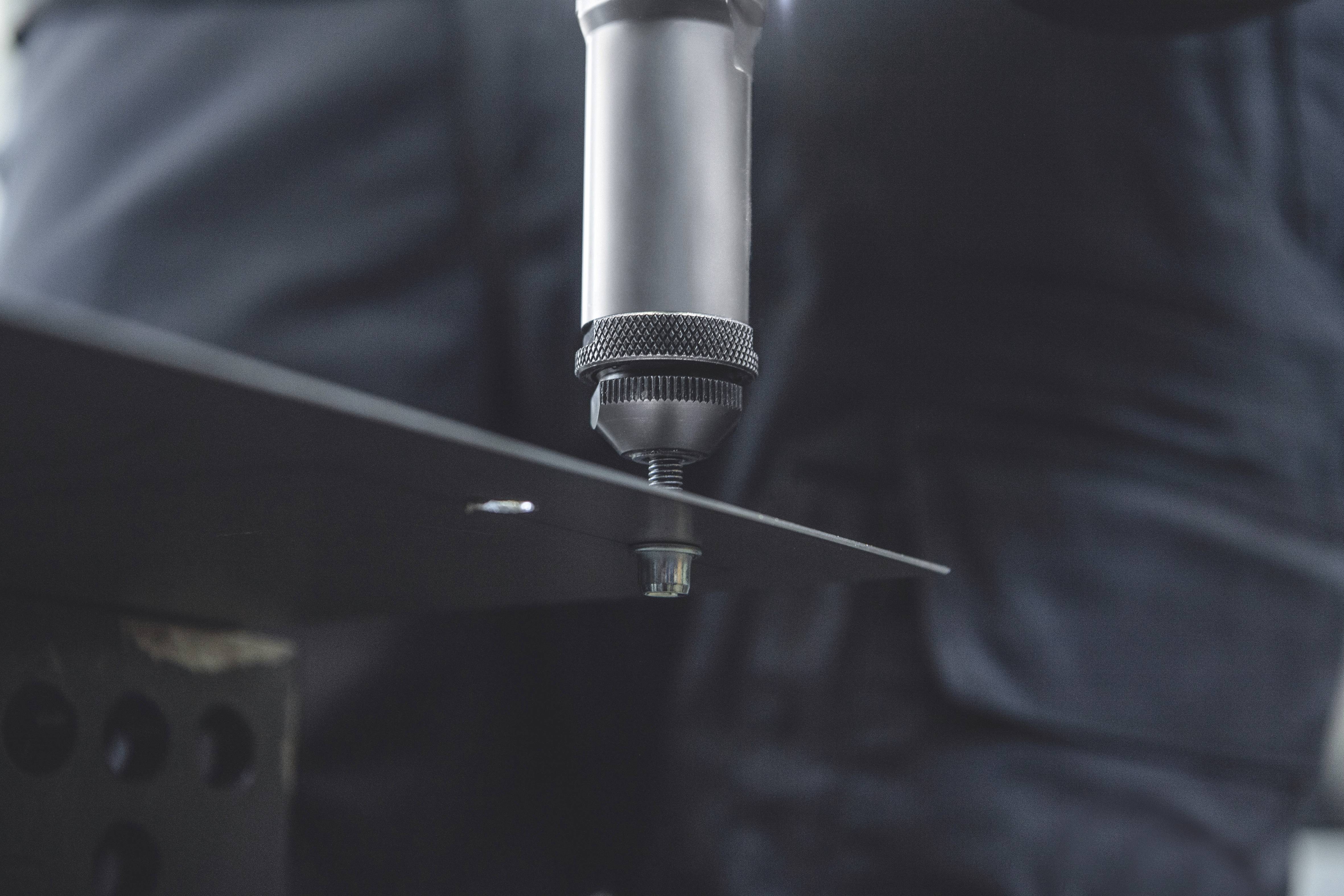 Nahaufnahme eines Werkzeugs, das eine Schraube in ein Metallblech schraubt. Der Fokus liegt auf der Handwerksarbeit und Präzision.