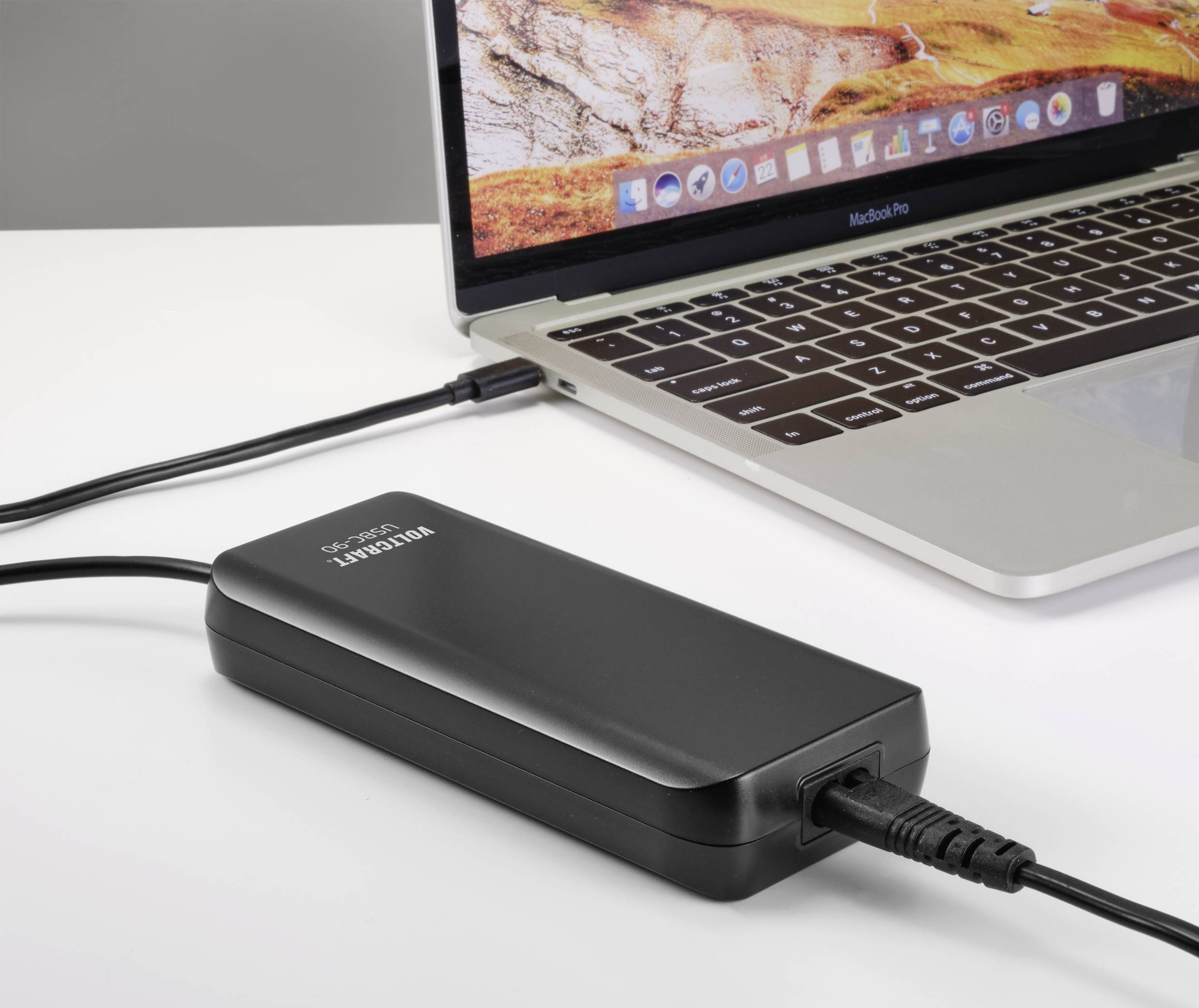 Ein Laptop wird über ein USB-Kabel von einer Powerbank geladen. Der Bildschirm des Laptops zeigt eine Landschaftsanzeige.
