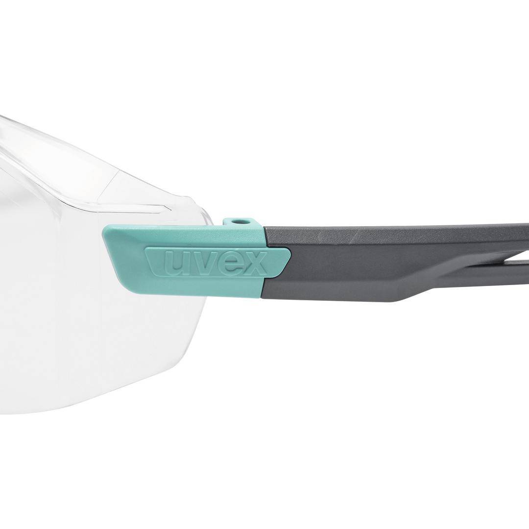 Schutzbrille mit transparenten Gläsern und grauen Bügeln, seitlich mit türkisfarbenem 'uvex' Logo.