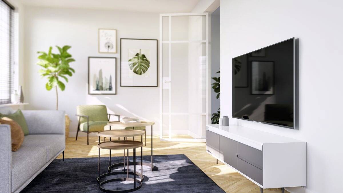 Modernes Wohnzimmer mit einem grauen Sofa, drei runden Tischen, einem großen Fernseher an der Wand und Pflanzen; helle, minimalistische Einrichtung.