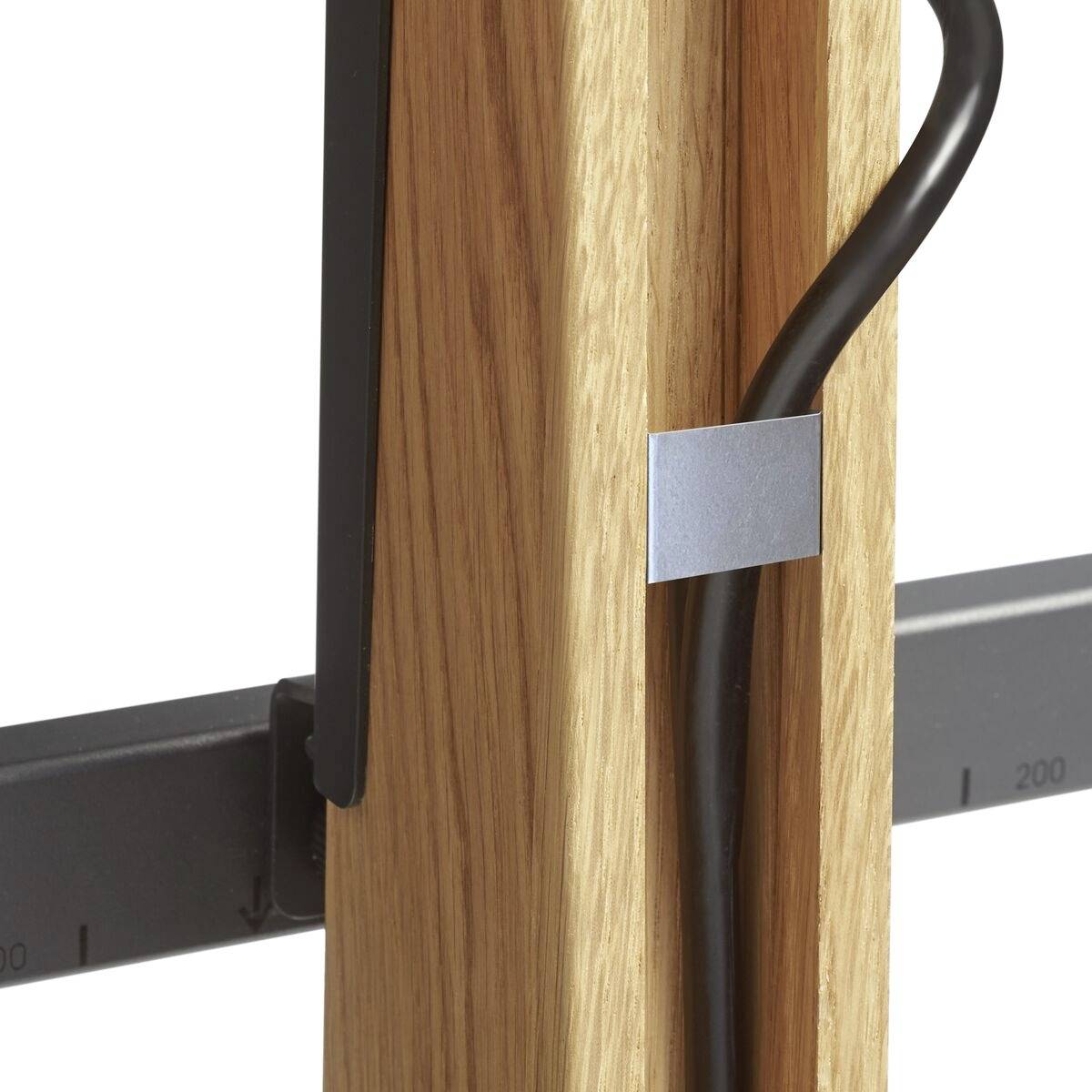 Kabel, das mit einer Metallklammer an einem Holzrahmen befestigt ist. Daneben ist ein Lineal mit Maßangaben zu sehen.