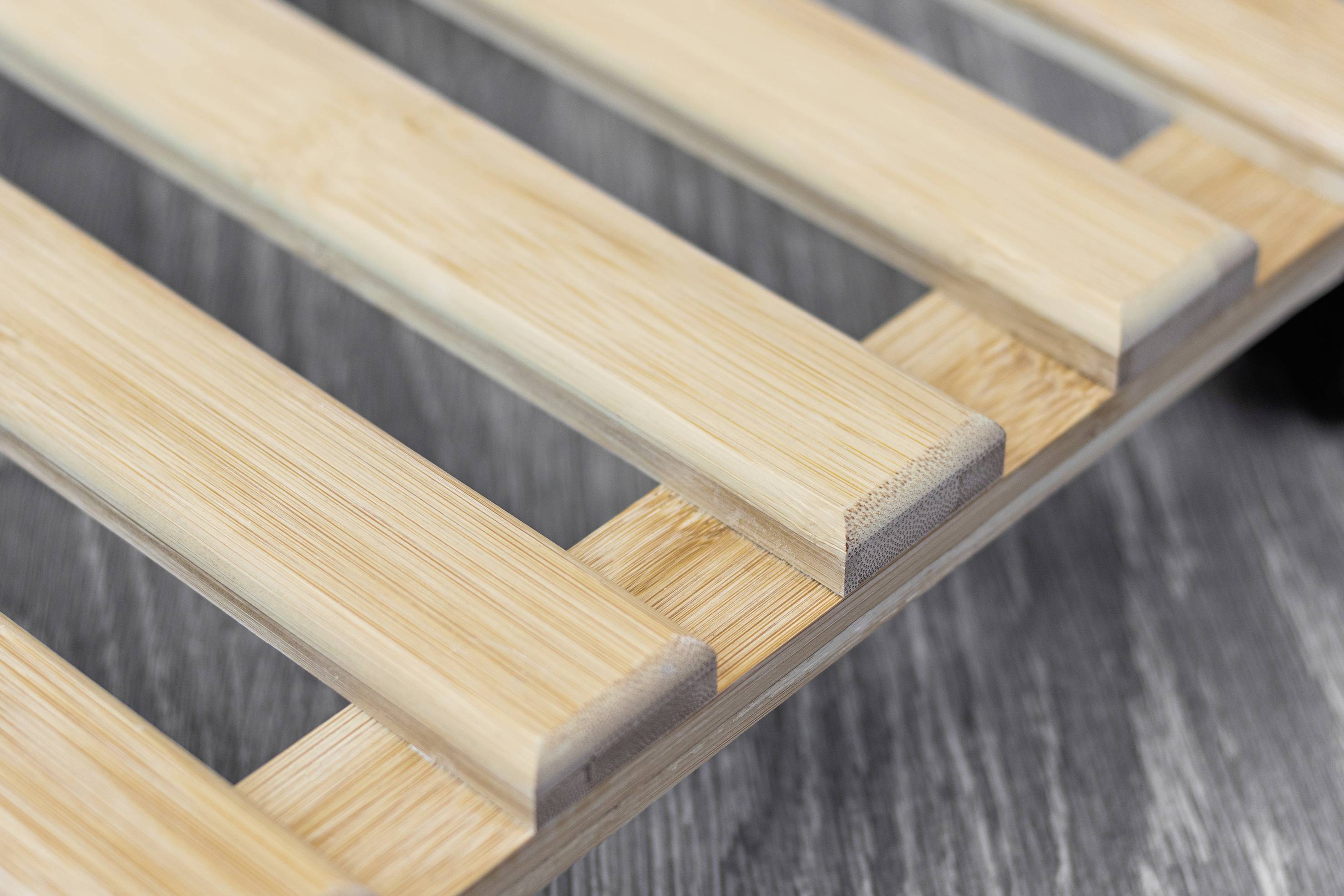 Holzlattenrost auf grauem Boden, Nahaufnahme.