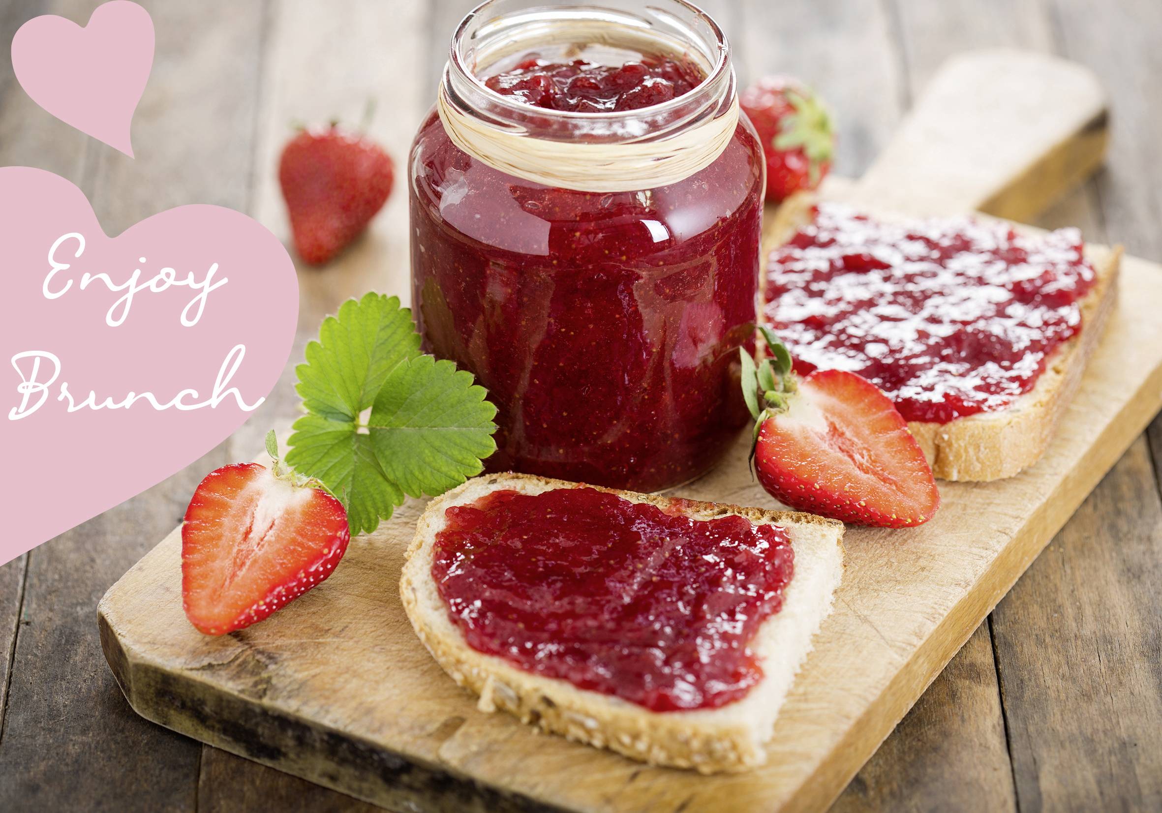 Ein rustikales Holzbrett mit einem geöffneten Glas Erdbeermarmelade, zwei bestrichenen Brotscheiben und frischen Erdbeeren. Text: 'Enjoy Brunch'.