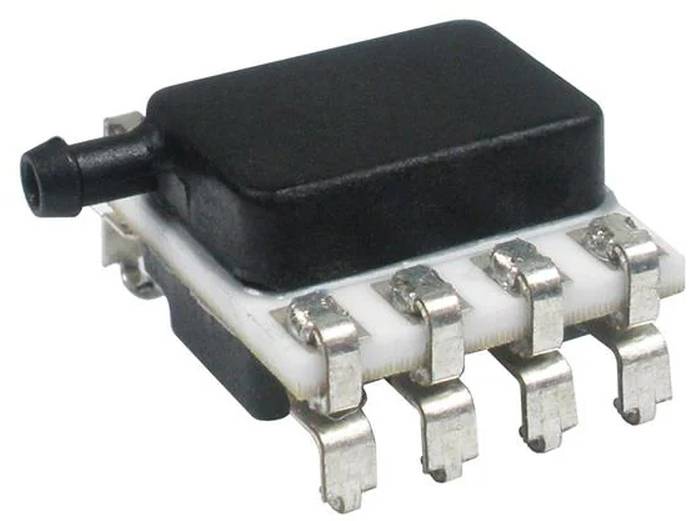 Eine kleine elektronische Komponente, die einem Sensor oder Chip ähnelt, mit einer schwarzen Oberseite, einer weißen Basis und mehreren Metallzacken an den Seiten.