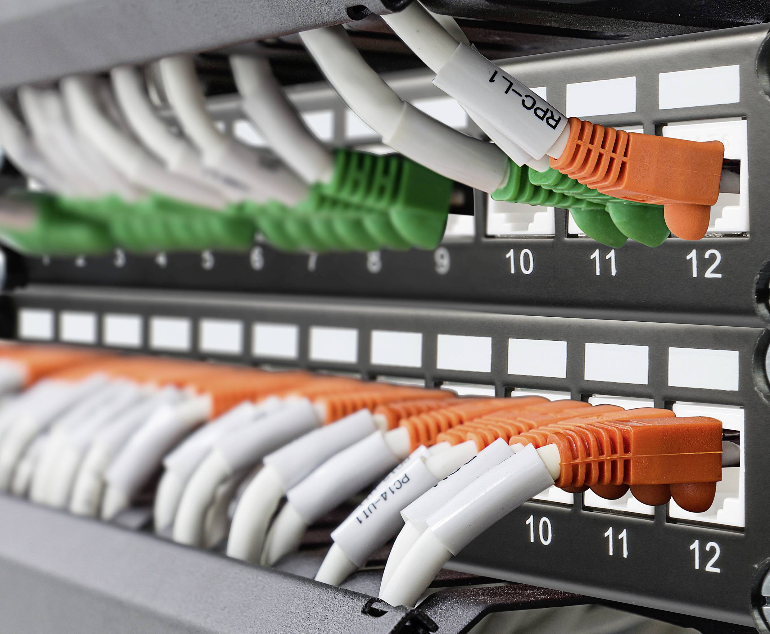 'Patchpanel mit farbcodierten Netzwerkkabeln, nummeriert von 9 bis 12. Verbundenes Kabel mit Beschriftung 
