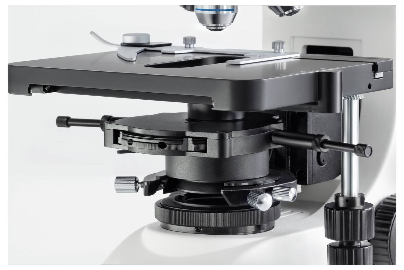 Nahaufnahme eines Mikroskoptisches mit Fokus auf dessen mechanische Komponenten wie Einstellräder und Objektträgerhalterung.