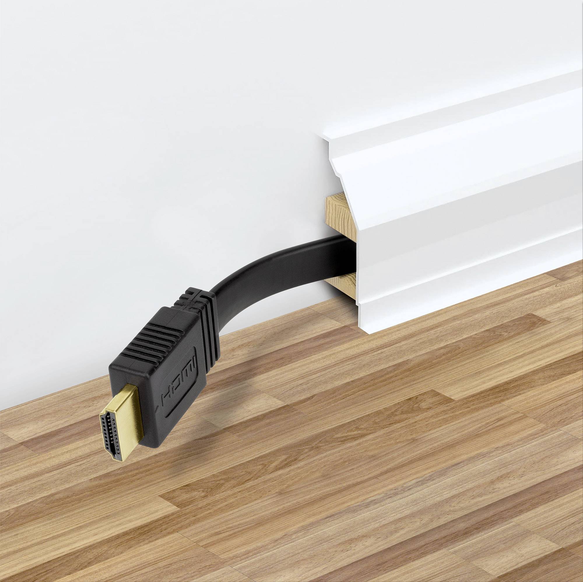 Ein HDMI-Kabel, das unter einer weißen Sockelleiste aus Holz hervorragt, liegt auf einem Laminatboden.