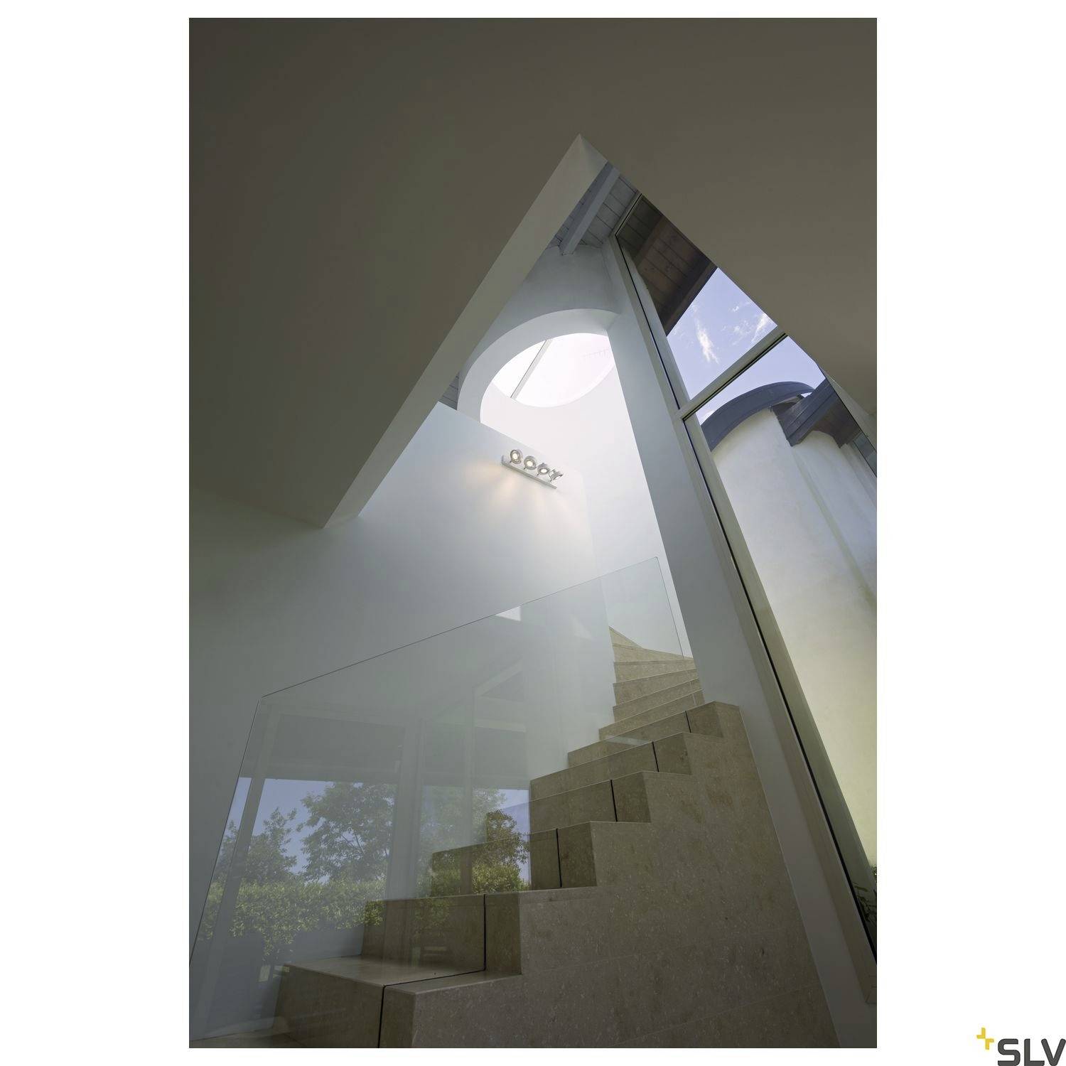 Innenansicht von modernen Treppen unter einem kreisförmigen Oberlicht. Große Fenster lassen viel natürliches Licht herein.