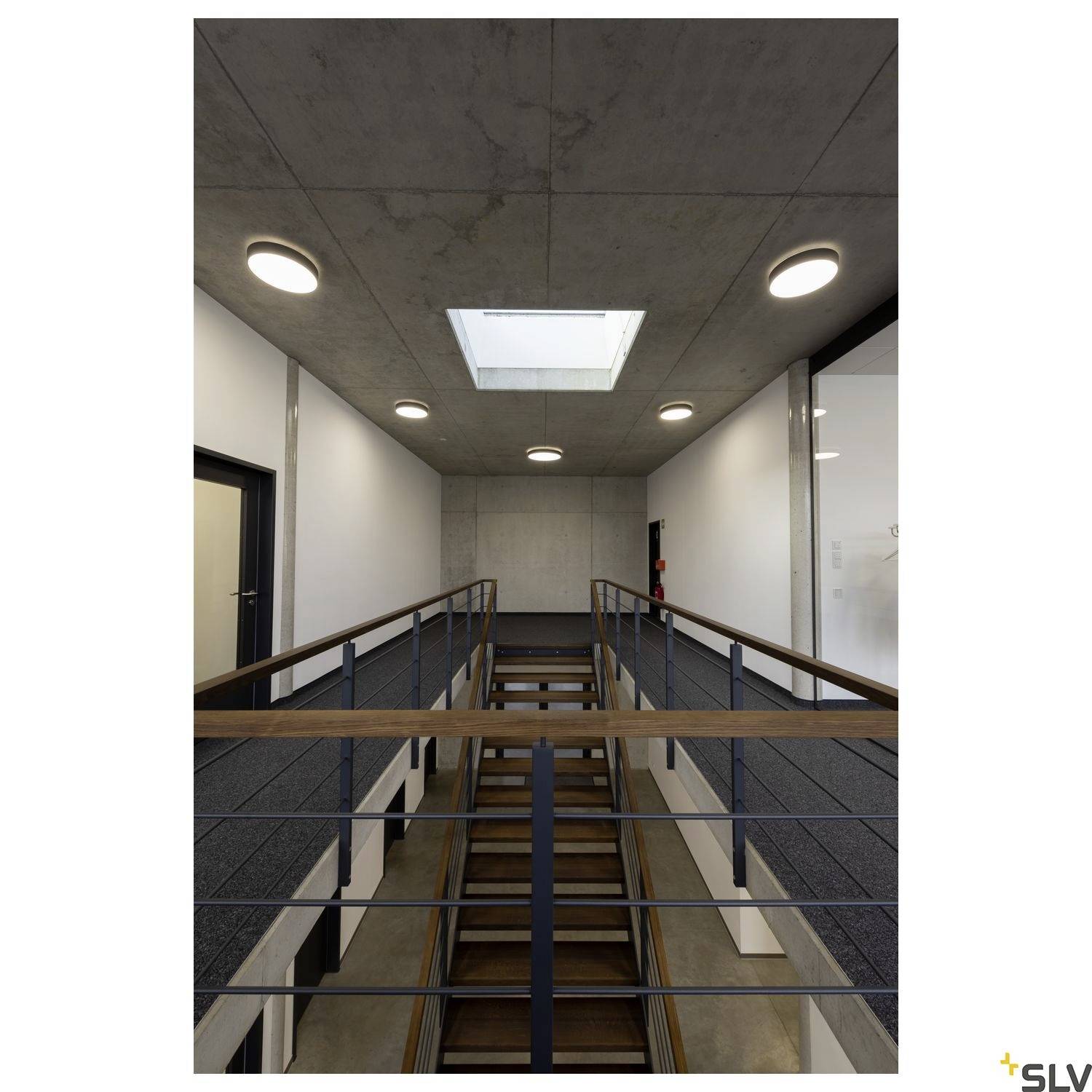 Ein moderner Innenbereich mit einer Metall- und Holztreppe führt zu einem Obergeschoss. Die Beleuchtung betont die klaren Linien und das minimalistische Design.