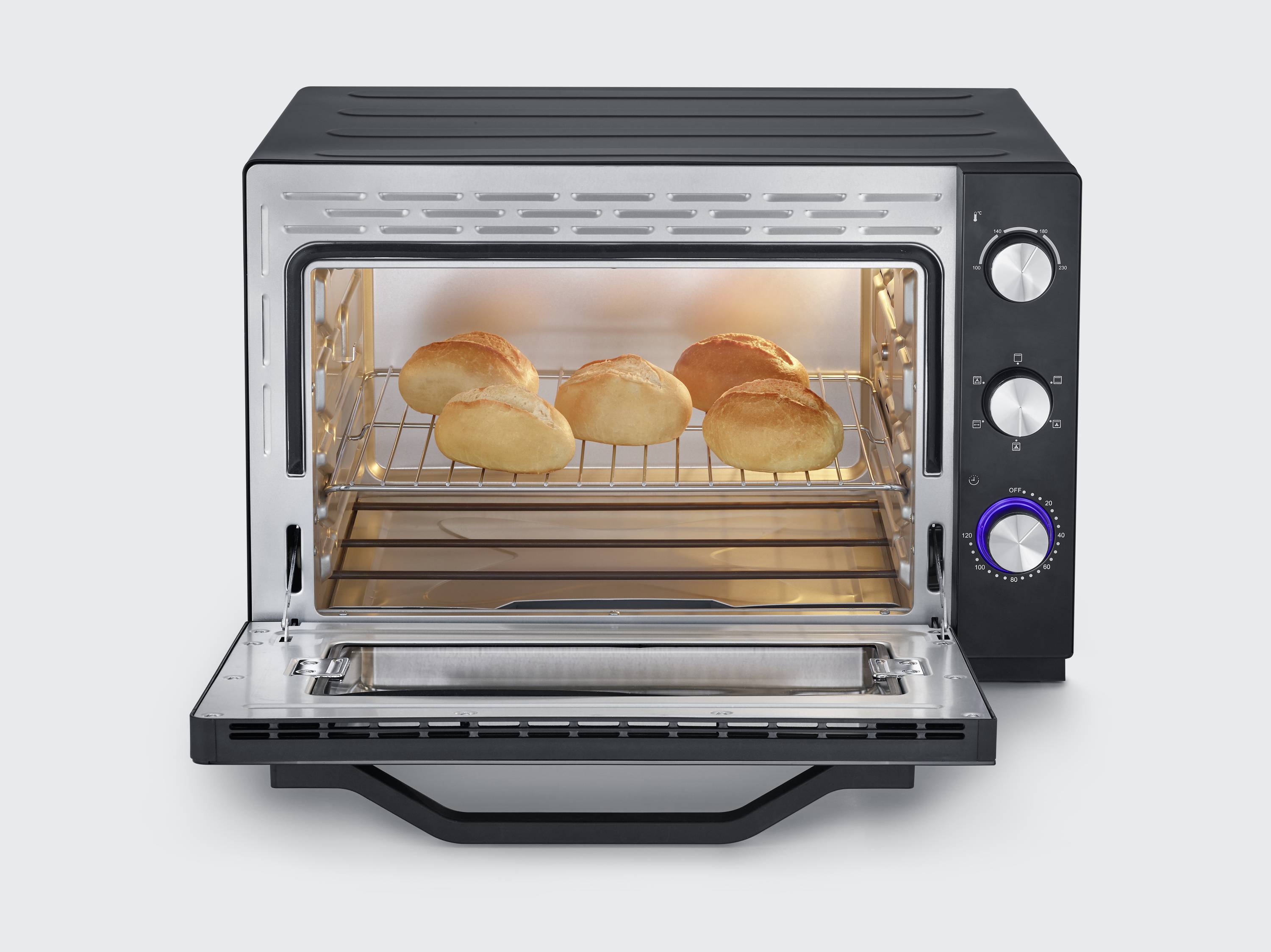 Ein geöffneter Toasterofen mit fünf goldbraunen Brötchen auf dem Rost, umgeben von einem modernen, schwarzen Gehäuse mit Drehknöpfen.