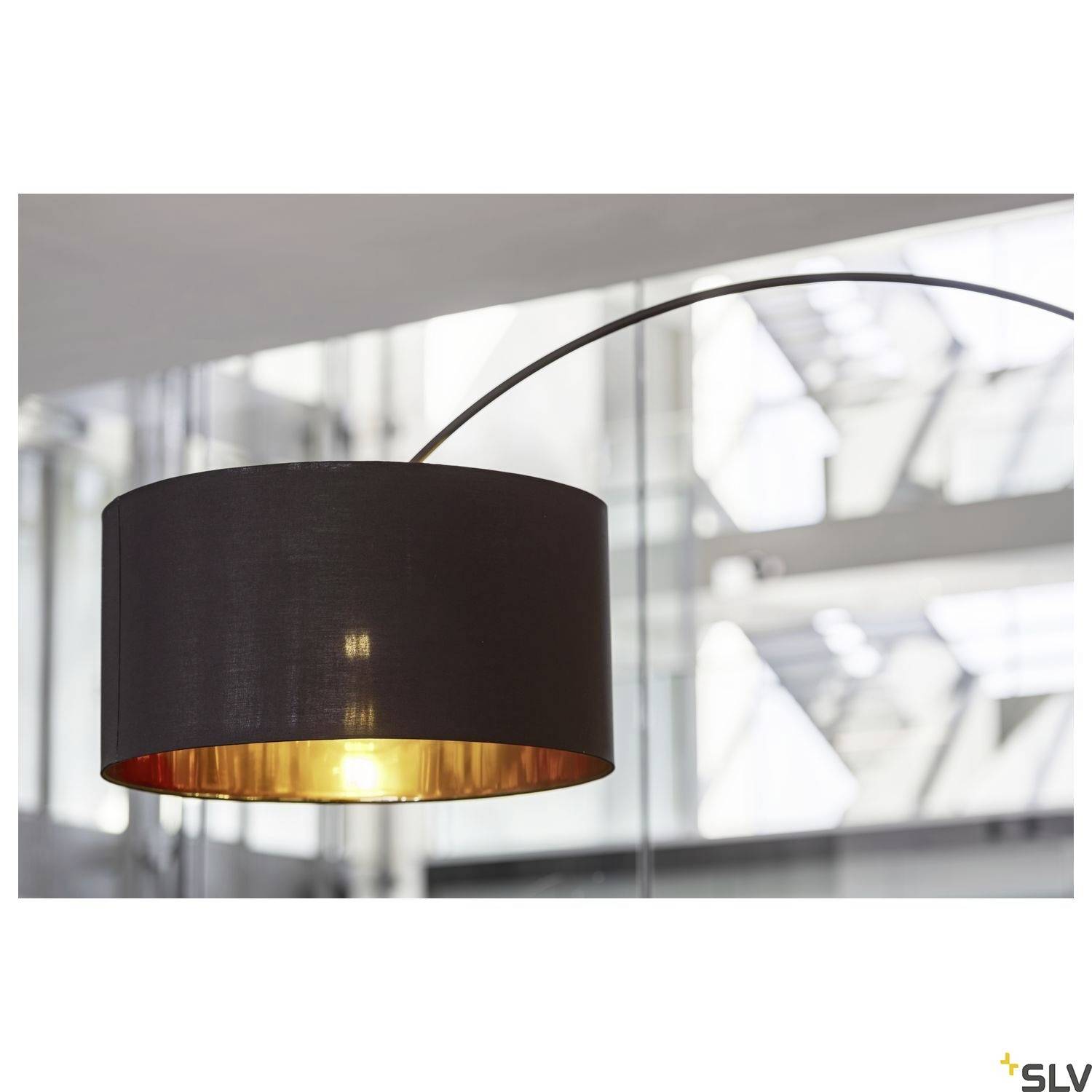 Moderne Stehlampe mit schwarzem Lampenschirm und goldenem Innenfutter, hängt in einem Büroumfeld mit Glaswänden.