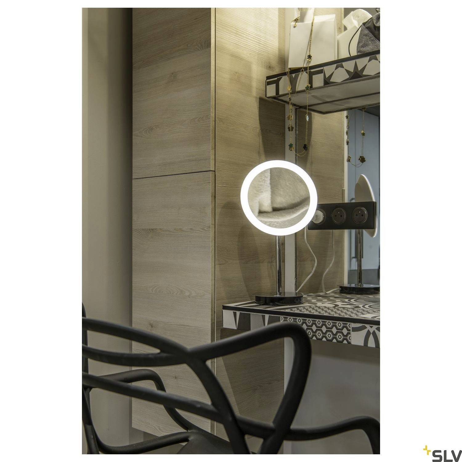 Ein Schminktisch mit beleuchtetem Spiegel in einem modernen Raum, Holzschränke und dekorative Elemente im Hintergrund.