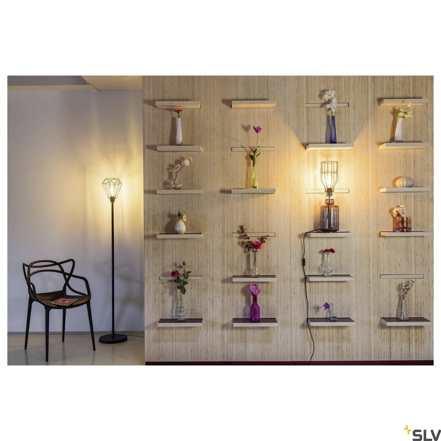 Eine Wand mit dekorativen Blumenvasen auf Regalen, flankiert von einem beleuchteten Stehlampenstuhl, schafft eine gemütliche Atmosphäre.