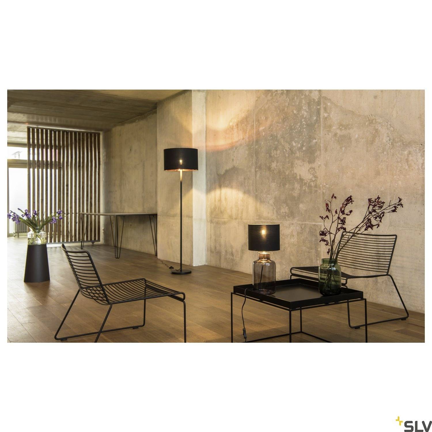 Ein moderner Raum mit Betonwänden, Holzlaminatboden, zwei schwarzen Gitterstühlen und einem Tisch. Stehlampe und Pflanzen dekorieren.