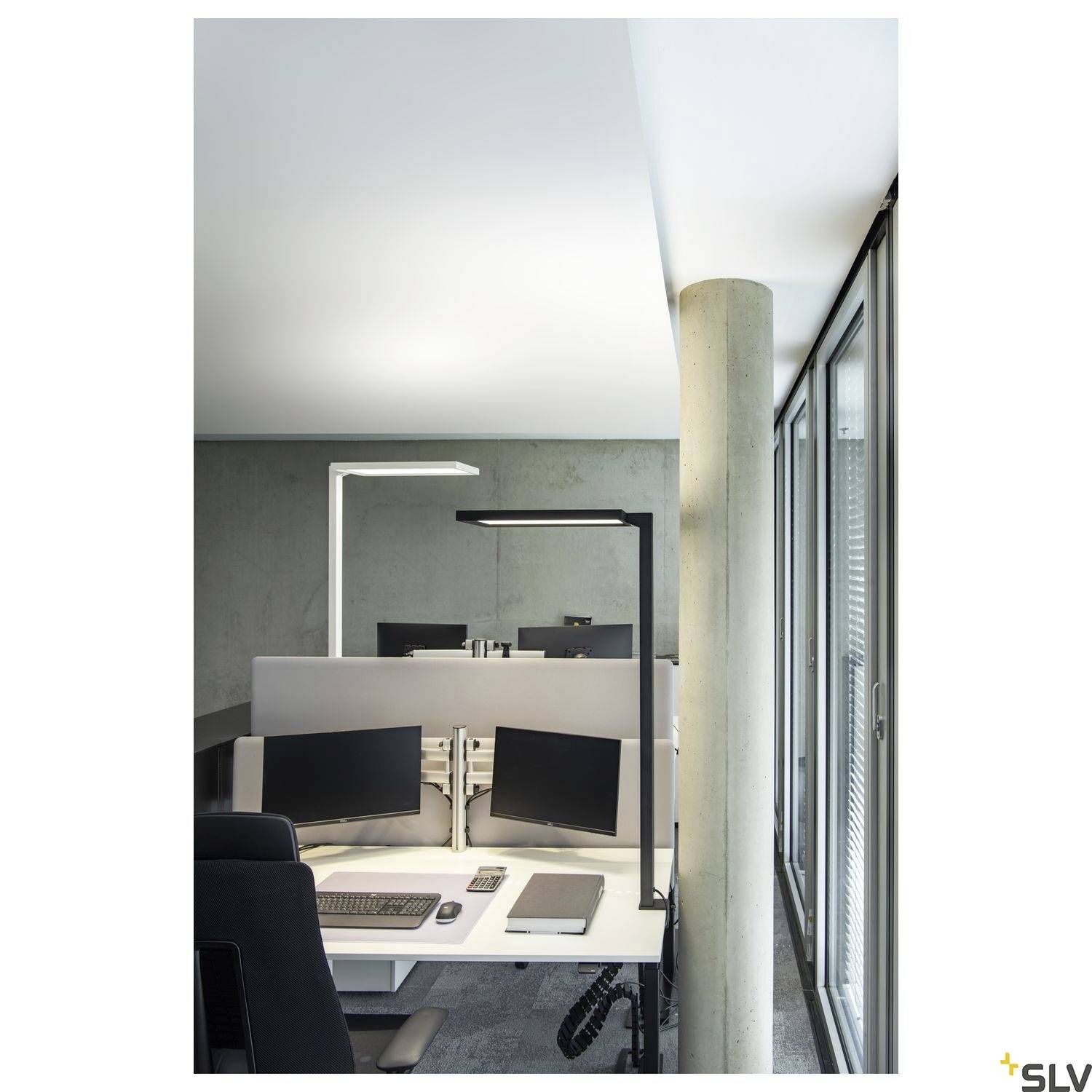 Modernes Büro mit Schreibtisch, zwei Monitoren, Tastatur und ergonomischem Stuhl, beleuchtet von einer Schreibtischlampe.