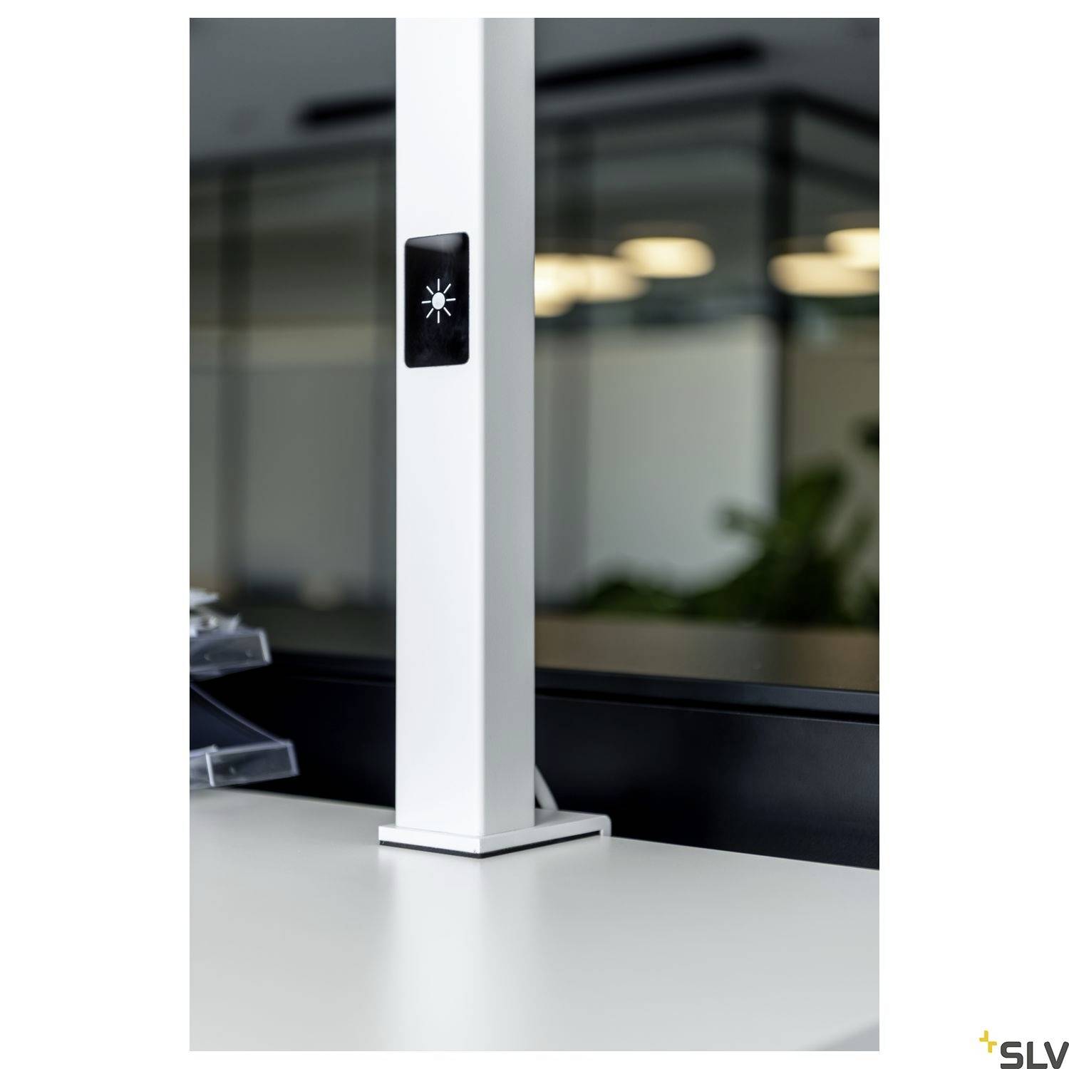 Heller Büroraum mit modernem Design; Fokus auf eine weiße Stehleuchte mit einem schwarzen, beleuchteten Symbol in der Mitte.