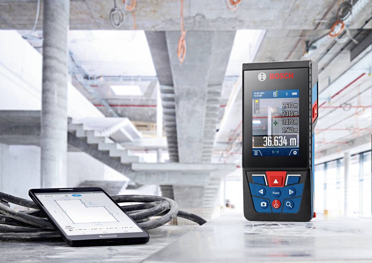 Laser-Entfernungsmesser auf Baustelle neben Tablet, das Baupläne zeigt. Beide Geräte unterstützen bei der Mess- und Planungstechnik.