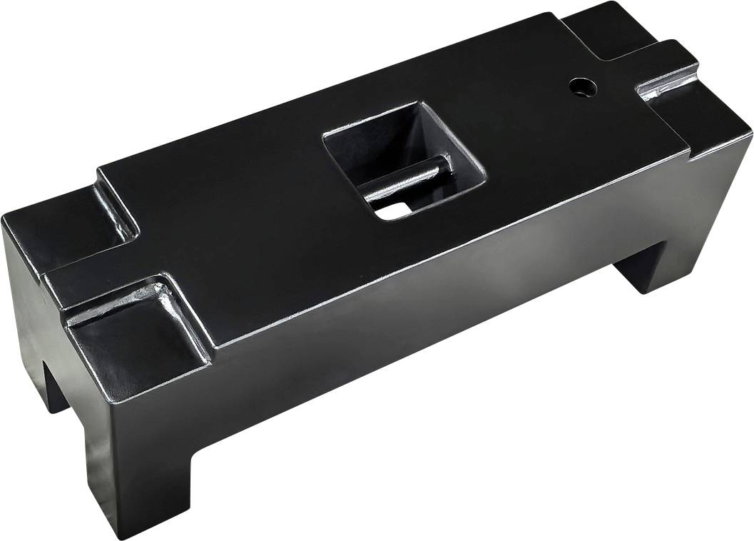 Ein rechteckiger, schwarzer Metallblock mit zentralem rechteckigem Loch und vier kurzen Standbeinen an jeder Ecke.