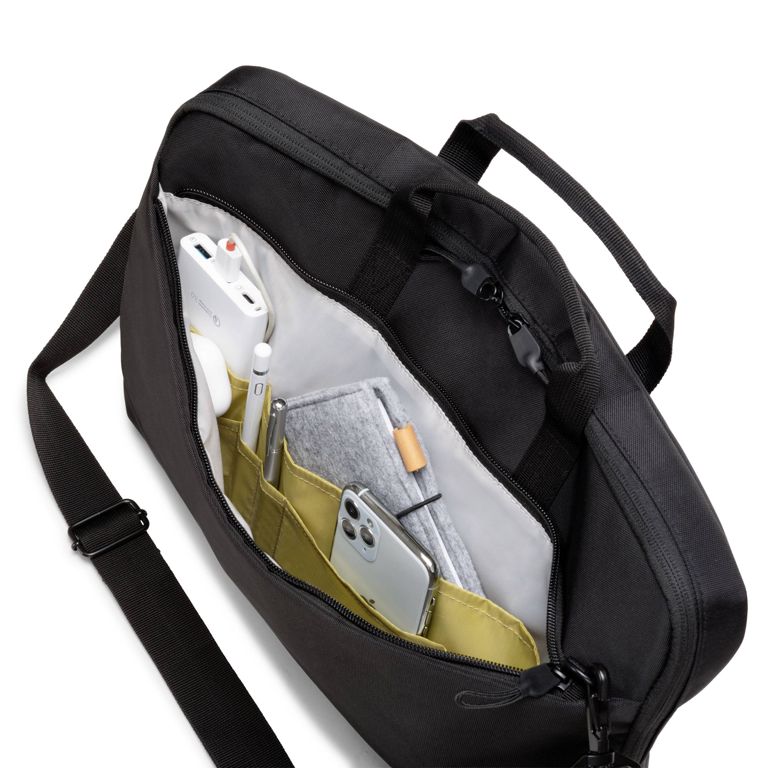 Eine schwarze Umhängetasche mit geöffneter Tasche zeigt darin verstaut elektronische Geräte, Stifte und Notizbücher.