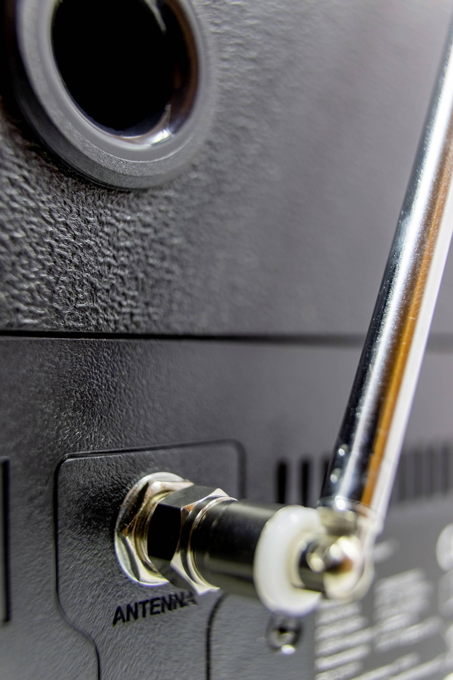 Nahaufnahme eines Funkgeräts mit angeschlossener Antenne, der Fokus liegt auf der Antennenbuchse und der Metallverbindung.