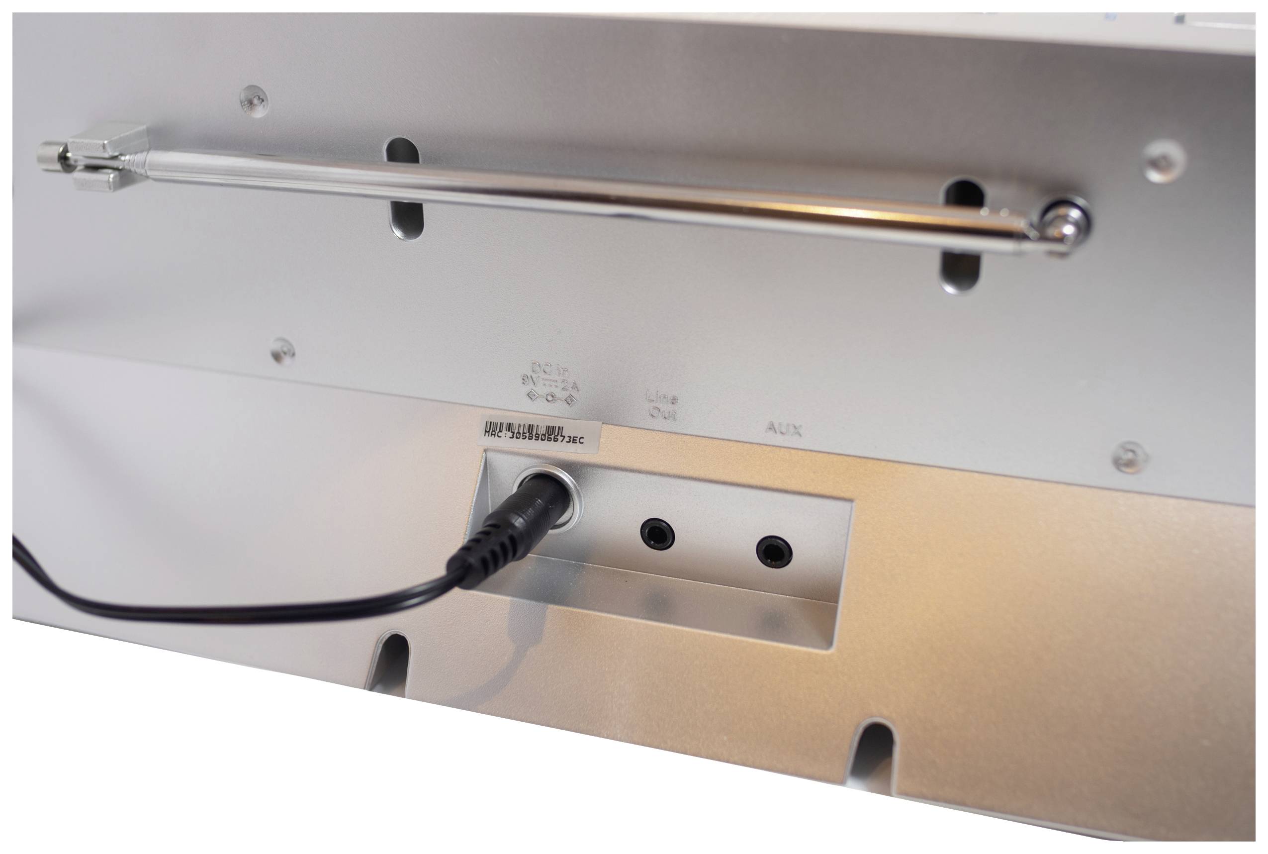 Die Rückseite eines elektronischen Geräts mit mehreren Anschlüssen, darunter ein Netzanschluss mit eingestecktem Stecker.