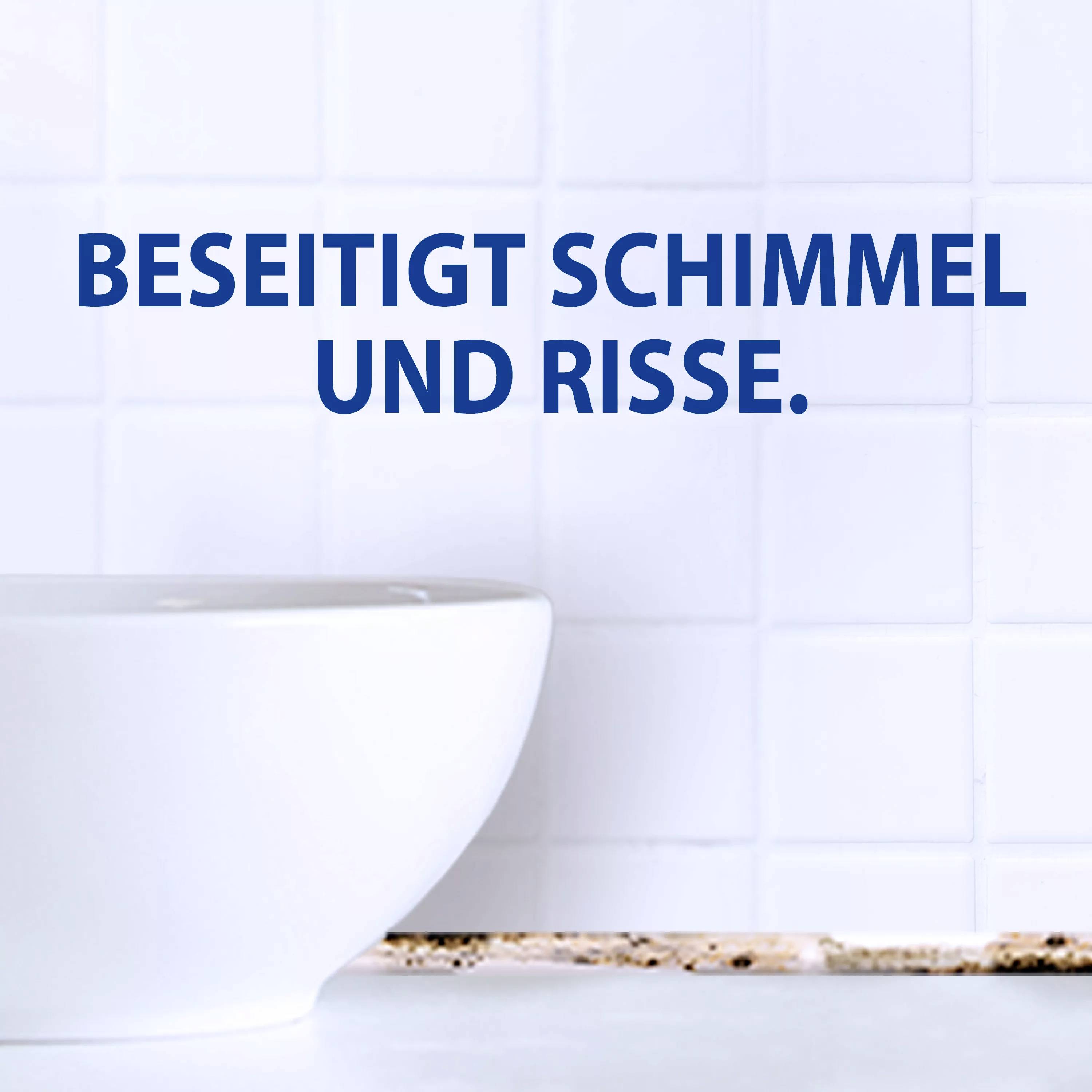 Weiße Fliesenwand mit blauem Text 'Beseitigt Schimmel und Risse'. Links im Bild ist der Rand einer weißen Schüssel sichtbar.