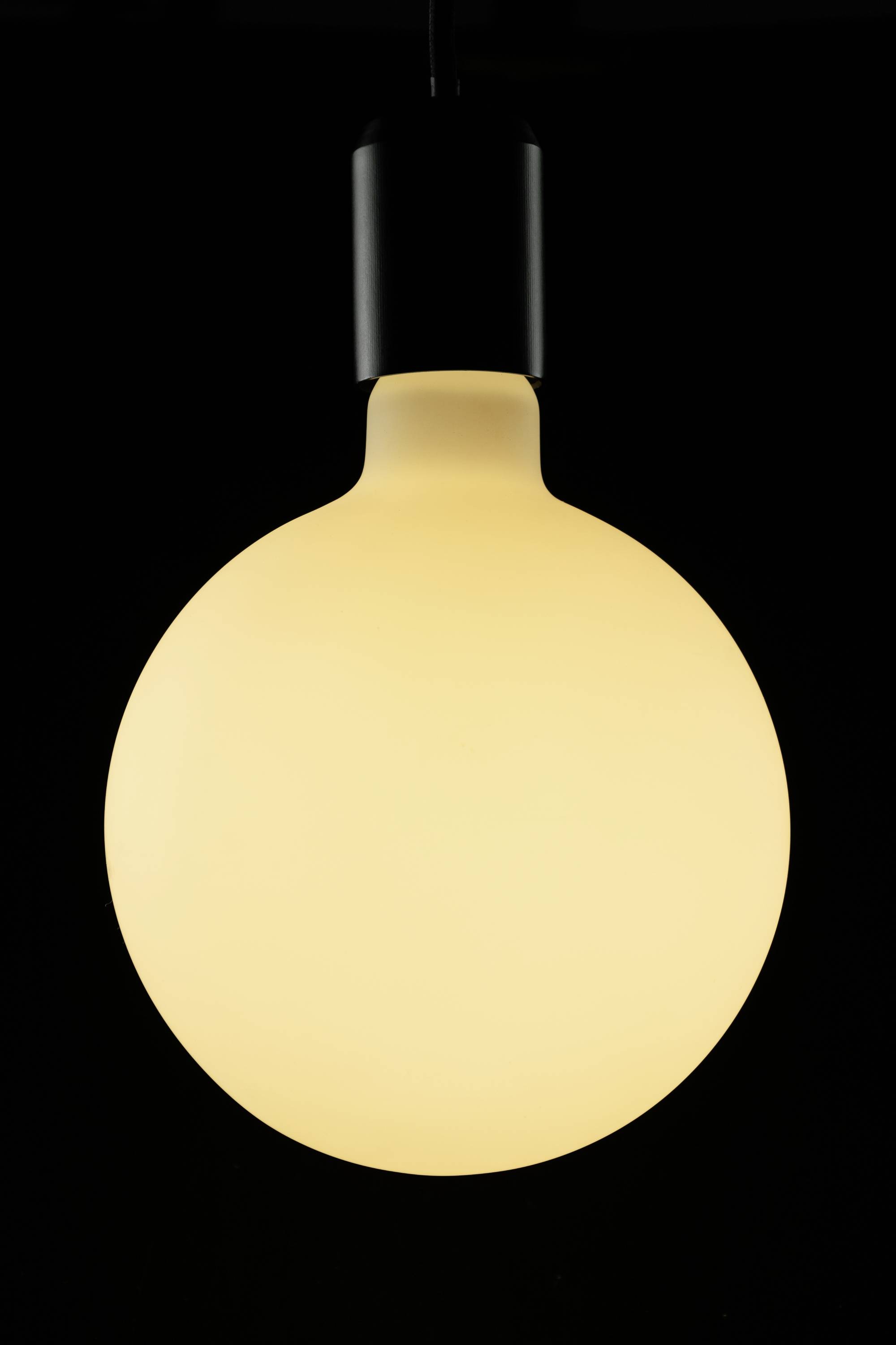 Glühlampe leuchtet hell in einem dunklen Raum, dominiert im Bild.