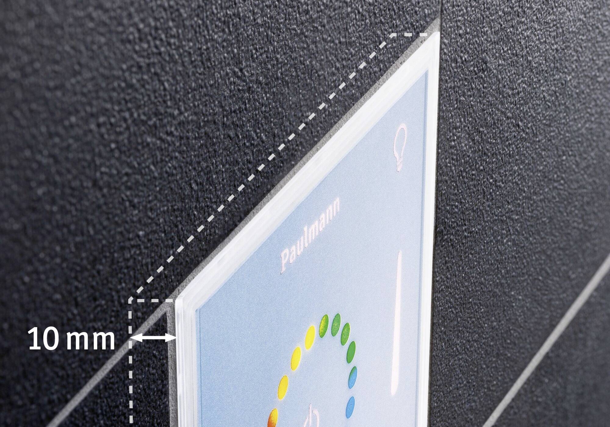 Schalter auf dunkler Wand; zeigt 'Paulmann' mit Farbkreis. Abstand zwischen Wand und Abdeckung beträgt 10 mm.