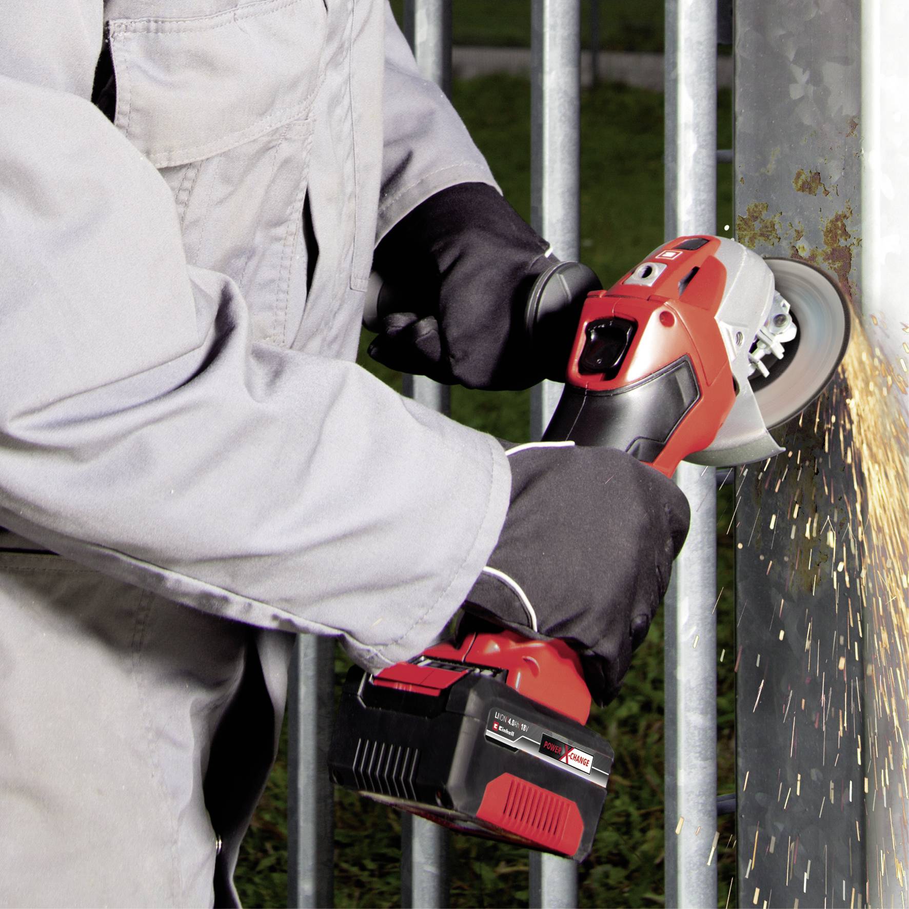 Eine Person schleift mit einem roten Winkelschleifer Metall, Funken sprühen seitlich. Sie trägt Handschuhe und Schutzkleidung.