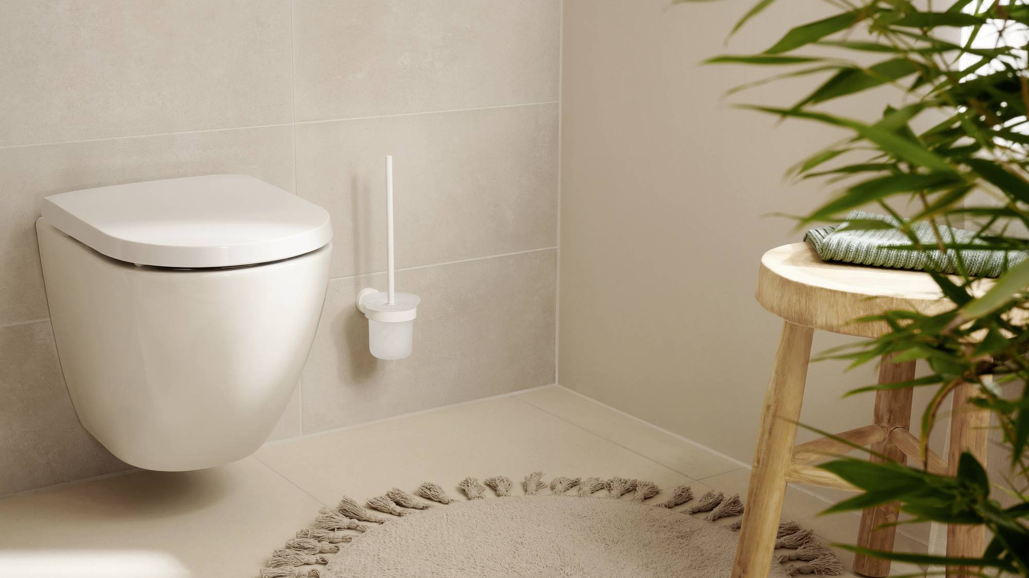 Moderne Badezimmeransicht mit Wandtoilette, rundem Teppich, Pflanzen und Holzstuhl. Helle und gemütliche Atmosphäre.