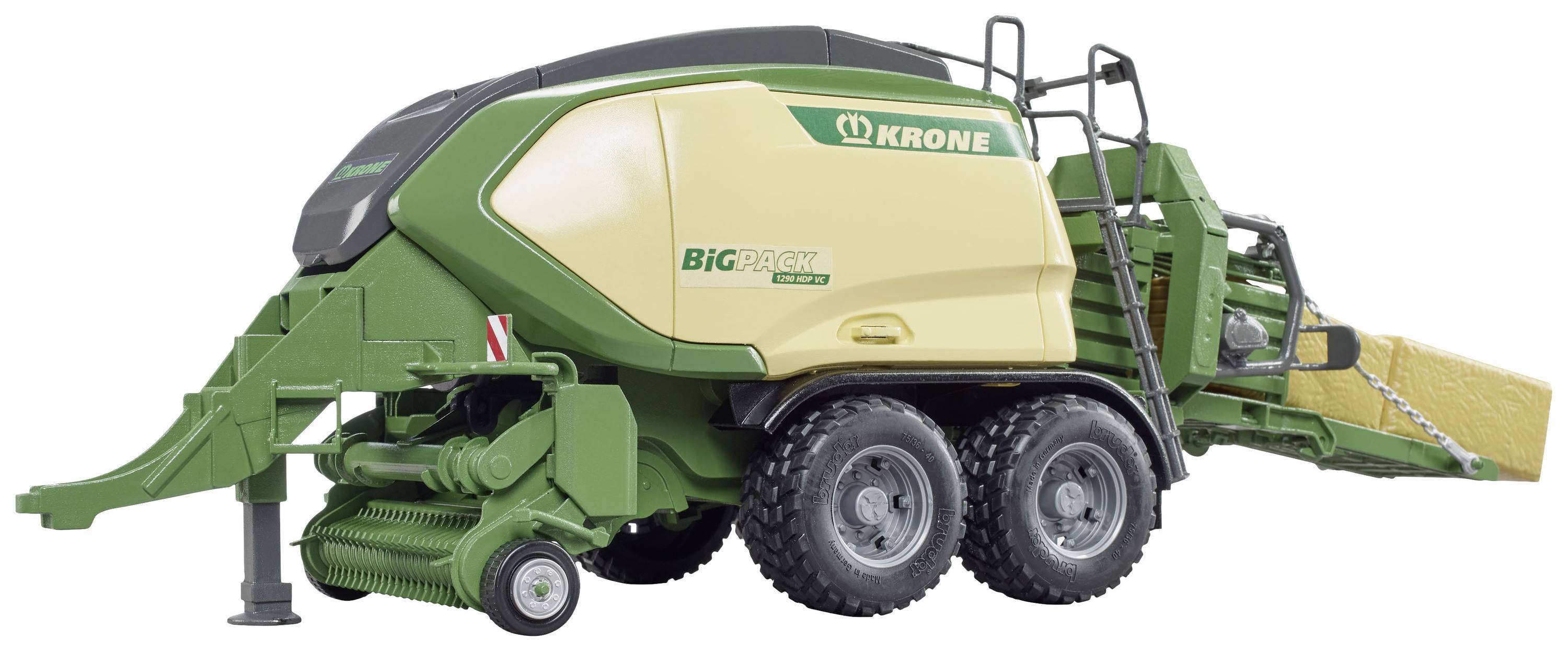 Grüne und cremefarbene landwirtschaftliche Ballenpresse von Krone mit zwei großen Rädern, Anhängevorrichtung und gelbem Heuballen.