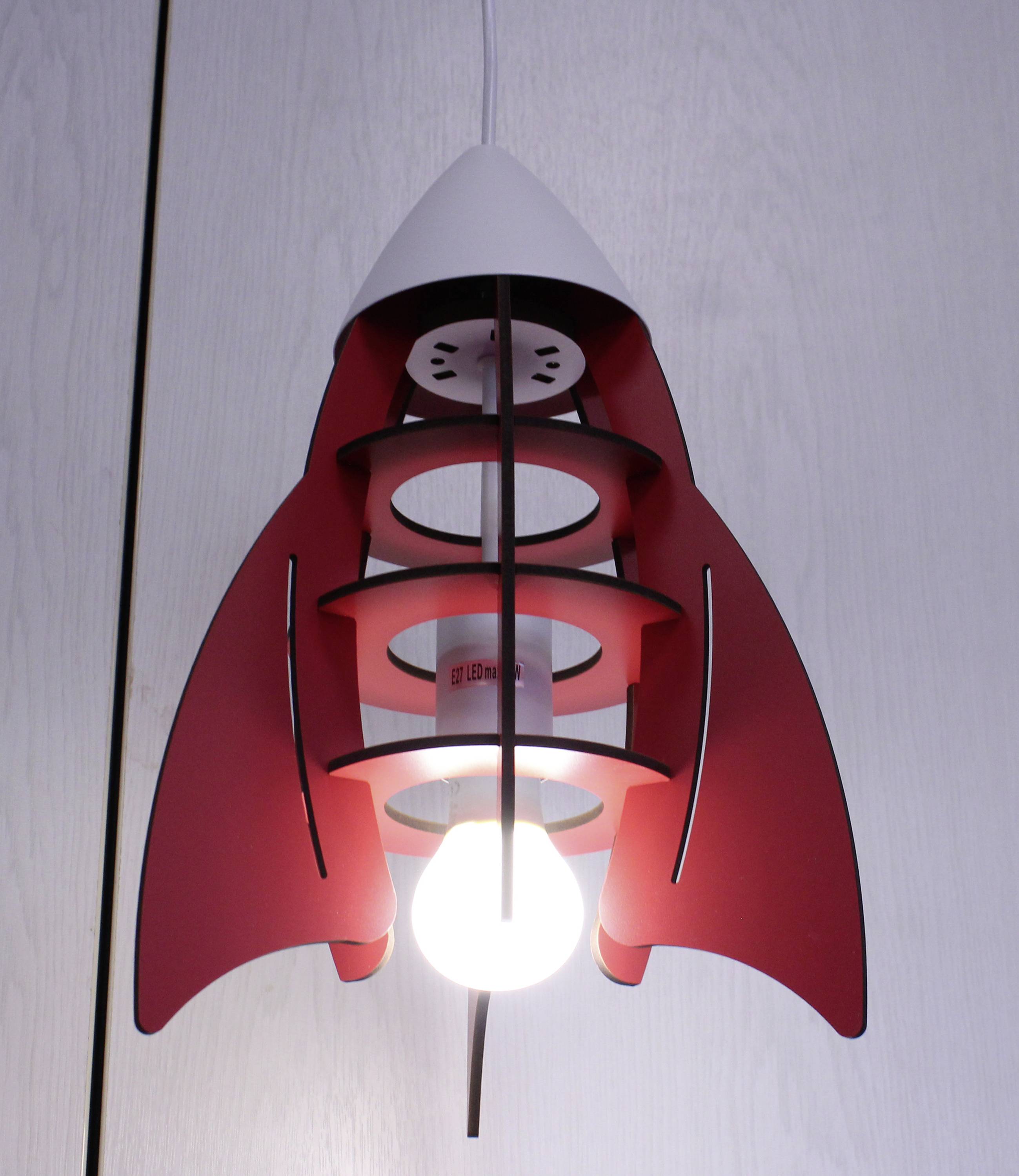 Eine lampe in form einer roten rakete hängt an der decke. Die Glühbirne leuchtet hell und ist das zentrale Element der Designlampe.