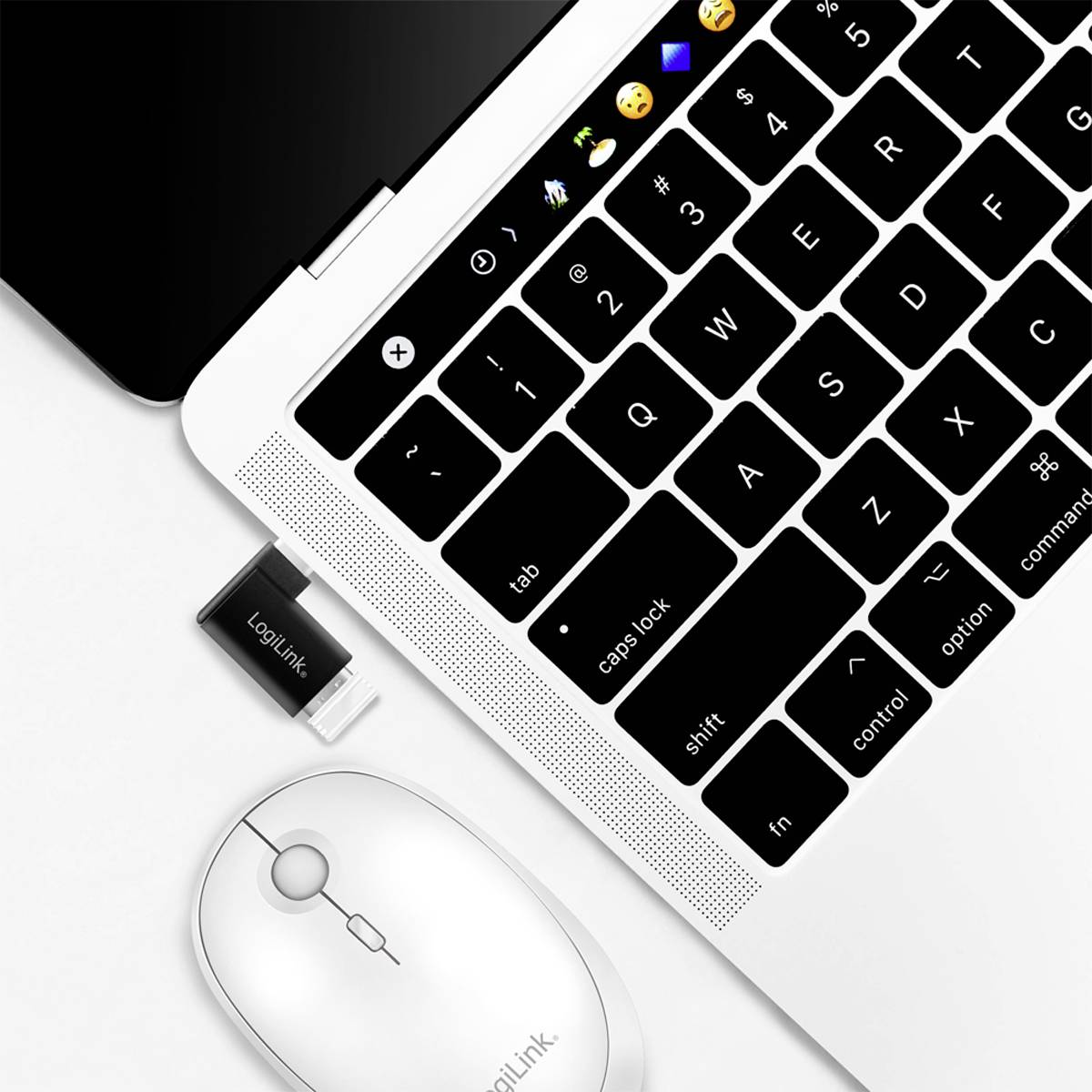 Eine drahtlose Logitech-Maus und ein USB-Empfänger liegen neben einer geöffneten Laptop-Tastatur auf einem weißen Hintergrund.