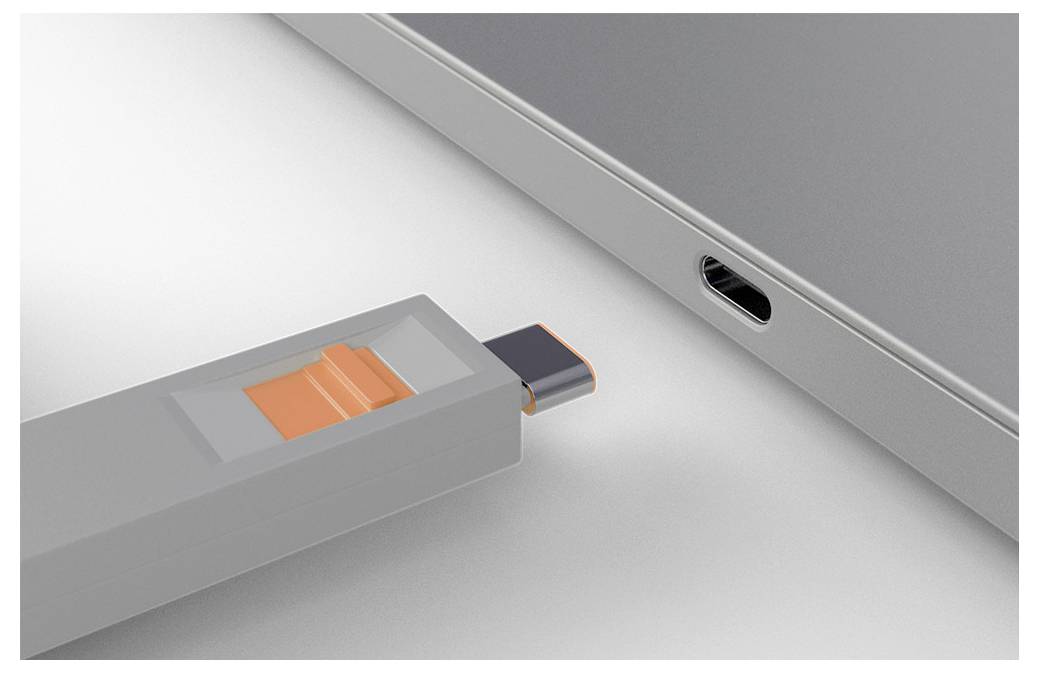 USB-Stick wird in einen seitlichen Port eines Laptops eingesteckt, mit dem sichtbaren orangen Schieber am Laufwerk.