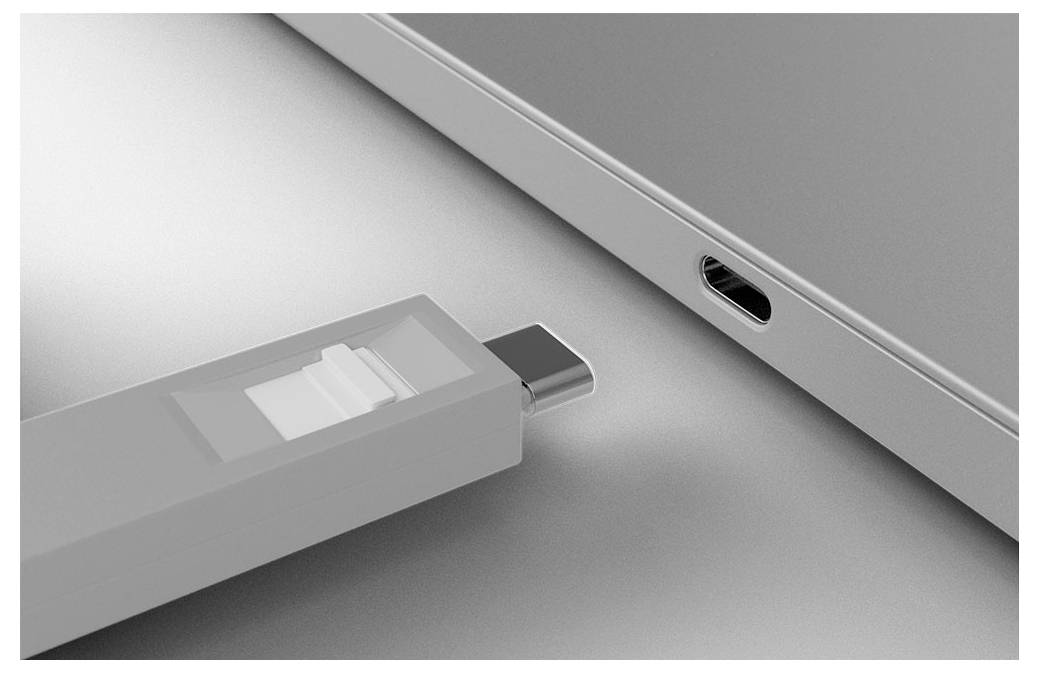 USB-Stick in den USB-C-Port eines Laptops eingesteckt, Nahaufnahme auf einer grauen Oberfläche dargestellt.
