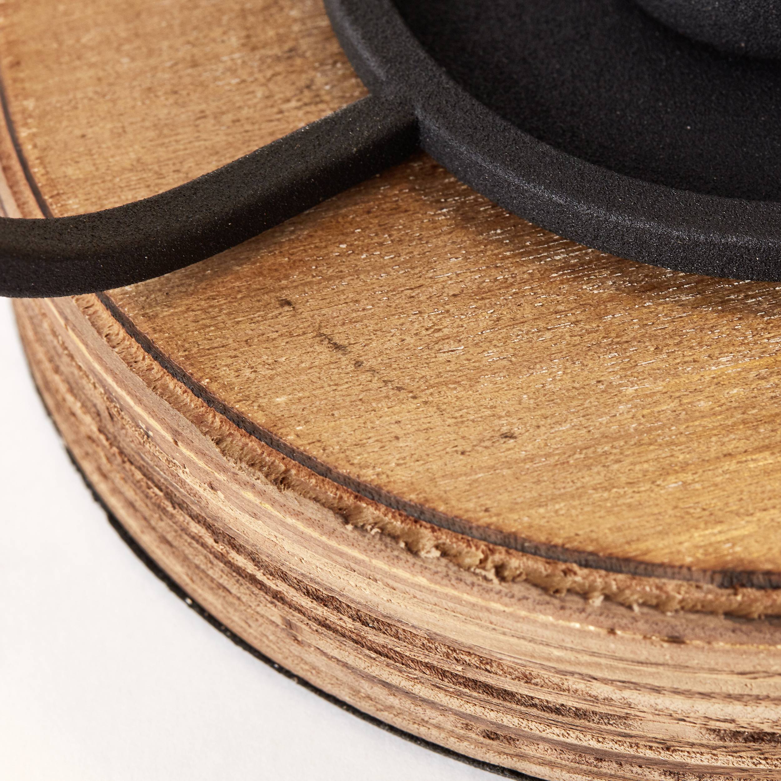 Ein gusseiserner Topfgriff auf einem hölzernen Untersetzer, Nahaufnahme. Verwendet für sicheres Kochen und heiße Topf-Platzierung.